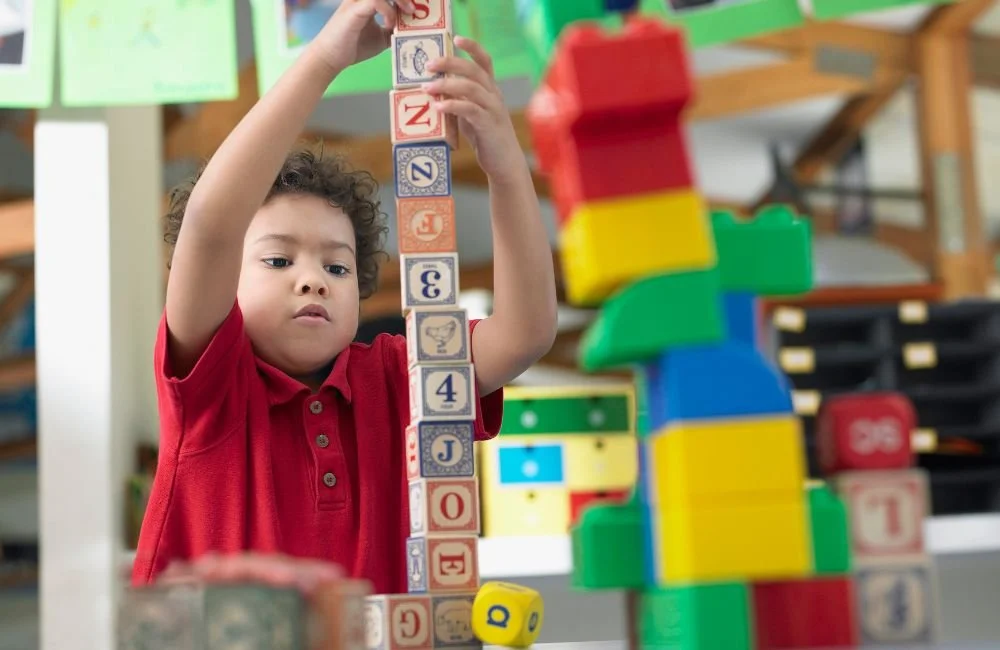 A little boy stacking number and letter wooden blocks in a Montessori classroom