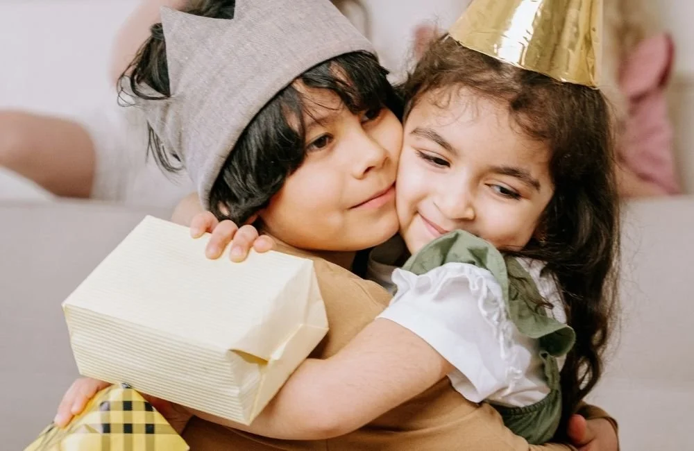 A little boy and girl hugging each other at a gift exchange | Orange Seeds Montessori Centre