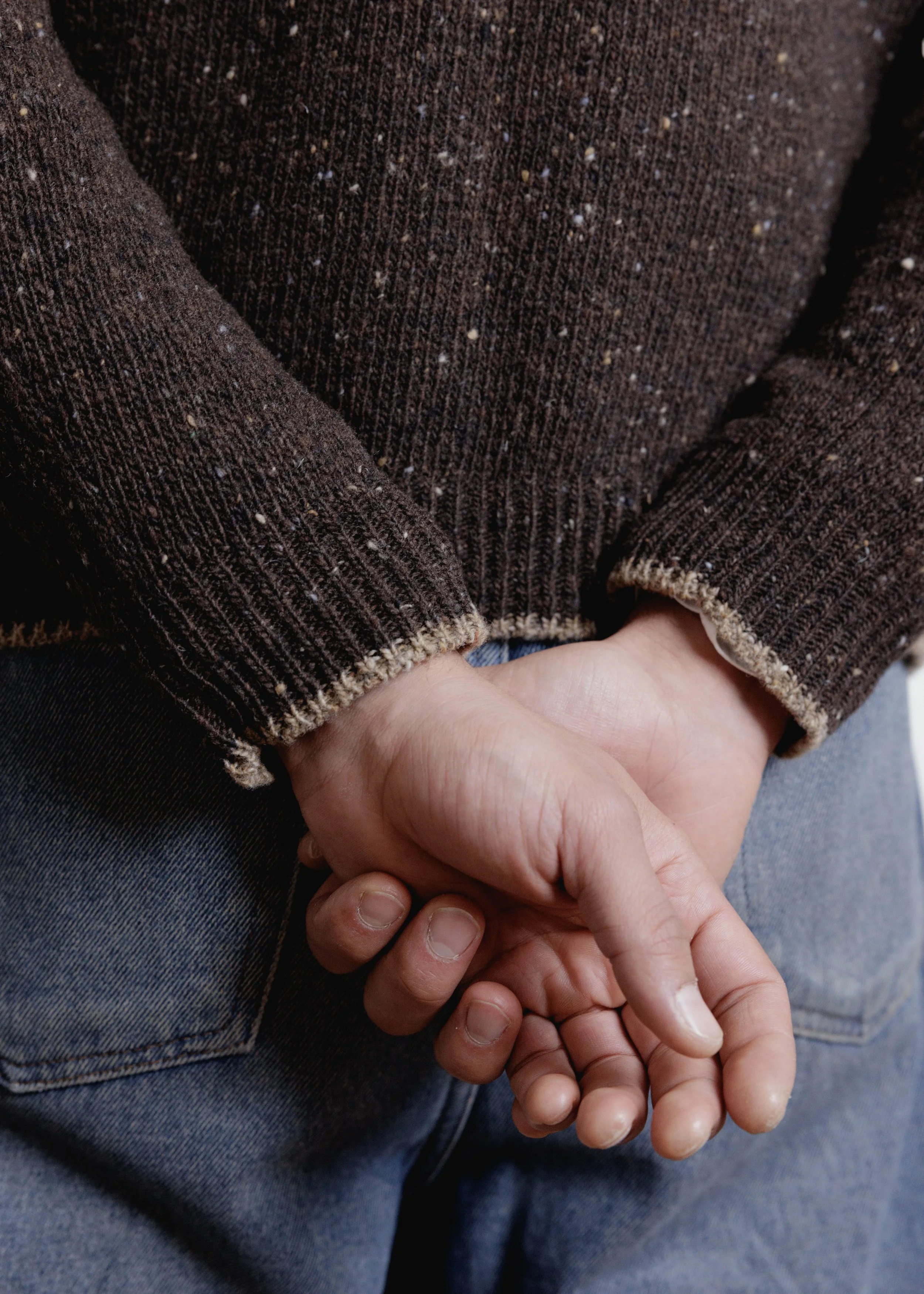 Everyday Raglan sweater in Chocolate, close-up of the cuffs, hands clasped behind the back