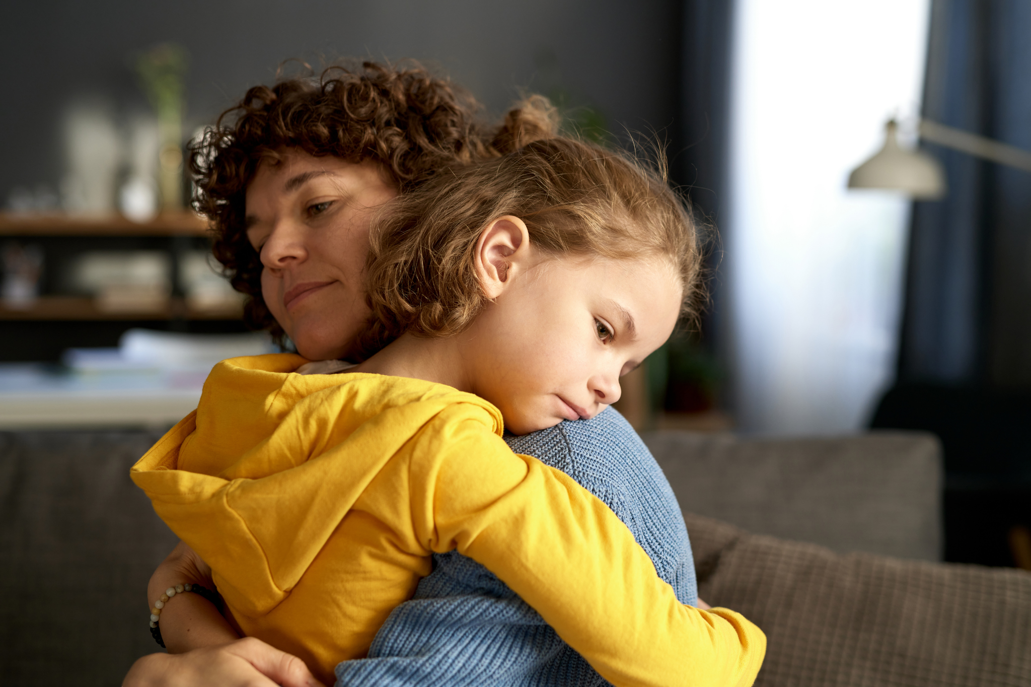 An adult woman embracing a child in a cozy living room in Portland, Oregon, or Seattle, Washington, symbolizing the warmth, comfort, and emotional security that define secure attachment."