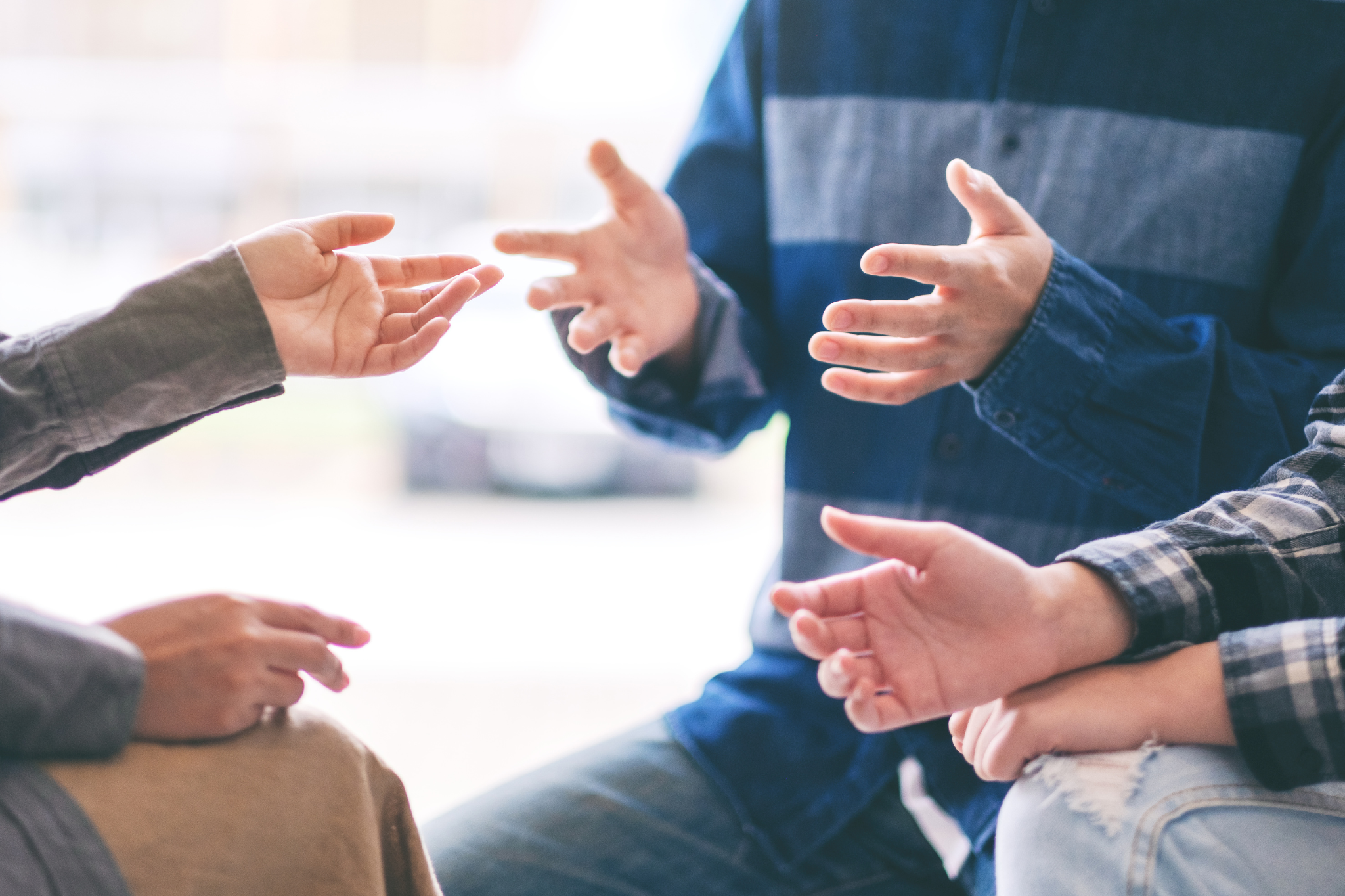 A close-up of animated hand gestures during an engaging group discussion reflects themes of communication and connection central to couples therapy, marriage counseling in Portland, Oregon, serving zip codes 97035, 97229, 97214, and 97210
