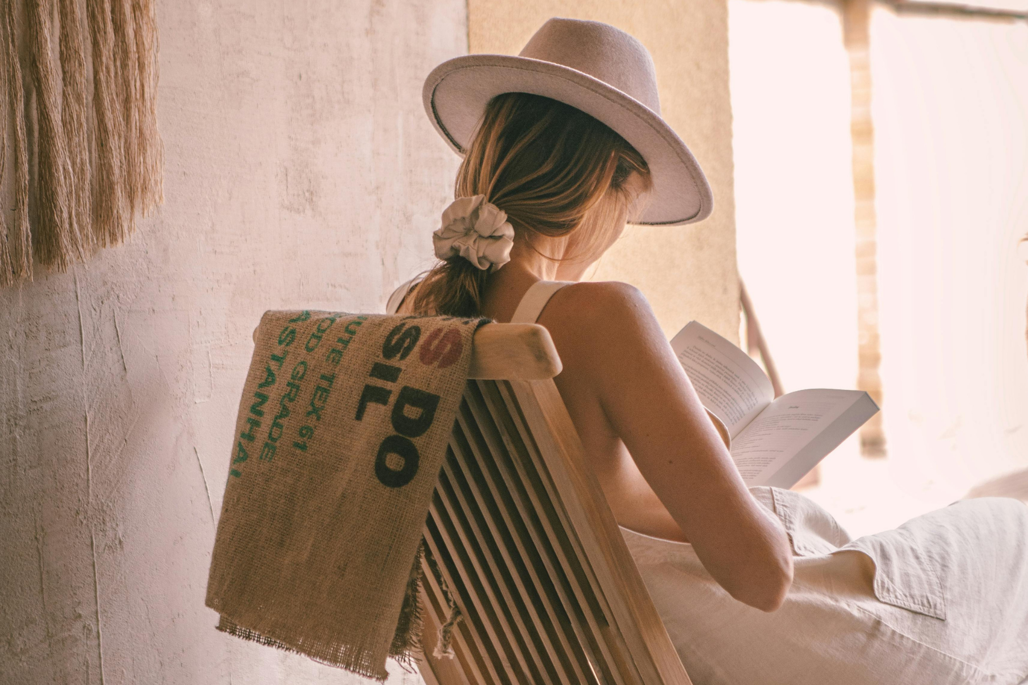 Woman in a sun hat reading by a window, reflecting on outgrowing your partner and relationship change in Portland, Oregon and Seattle, Washington.