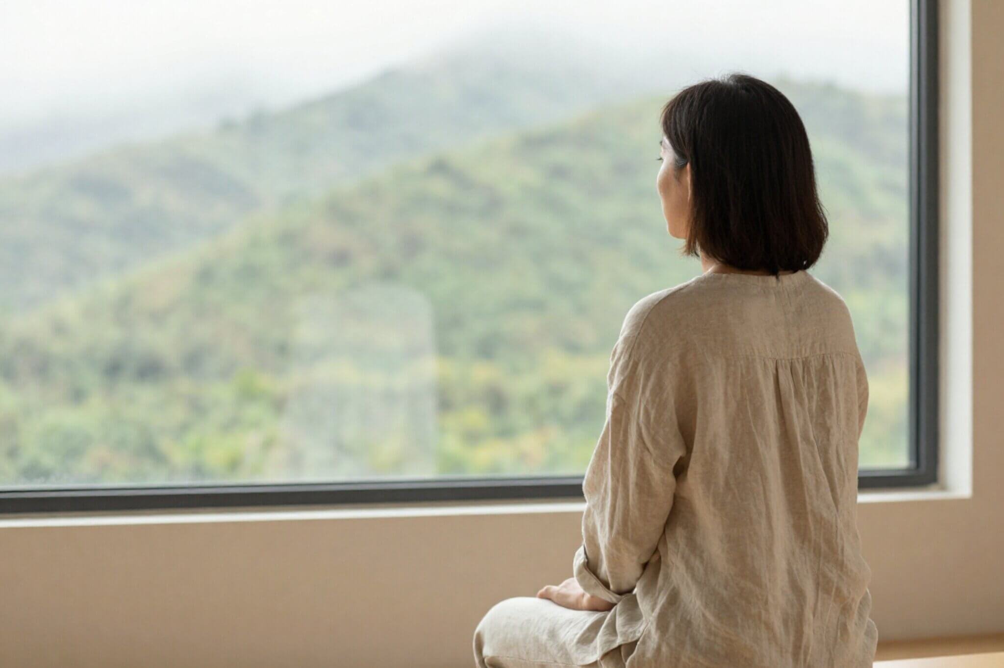 A woman with short brown hair sits by a large window facing mountains. A Seattle therapist shares how to fix job burnout. Learn more about workplace stress therapy here!