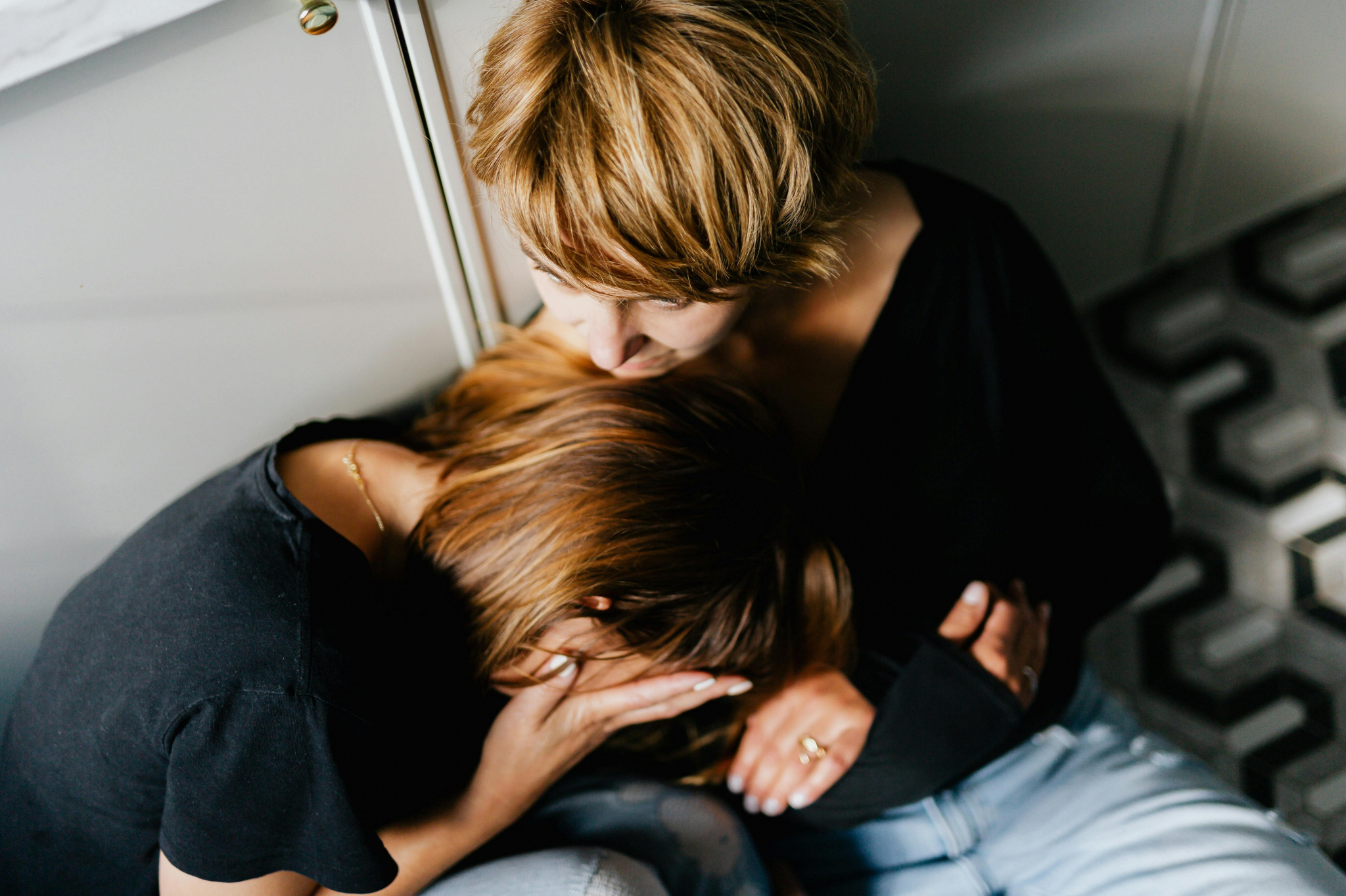 A comforting embrace between two women in Portland, Oregon, or Seattle, Washington, one offering support while the other appears distressed, reflecting the emotional vulnerability and need for reassurance in avoidant anxious attachment