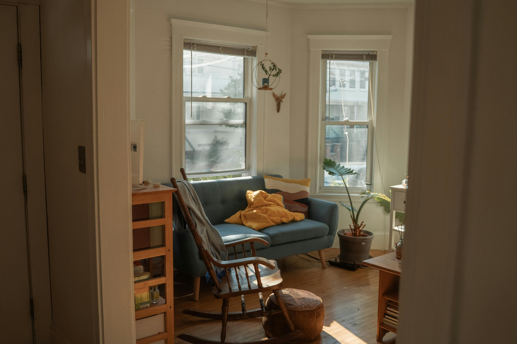 A cozy living room with a blue sofa, yellow blanket, and wooden rocking chair in Portland, Oregon, or Seattle, Washington, symbolizing the need for comfort and reassurance often sought by individuals with anxious attachment styles