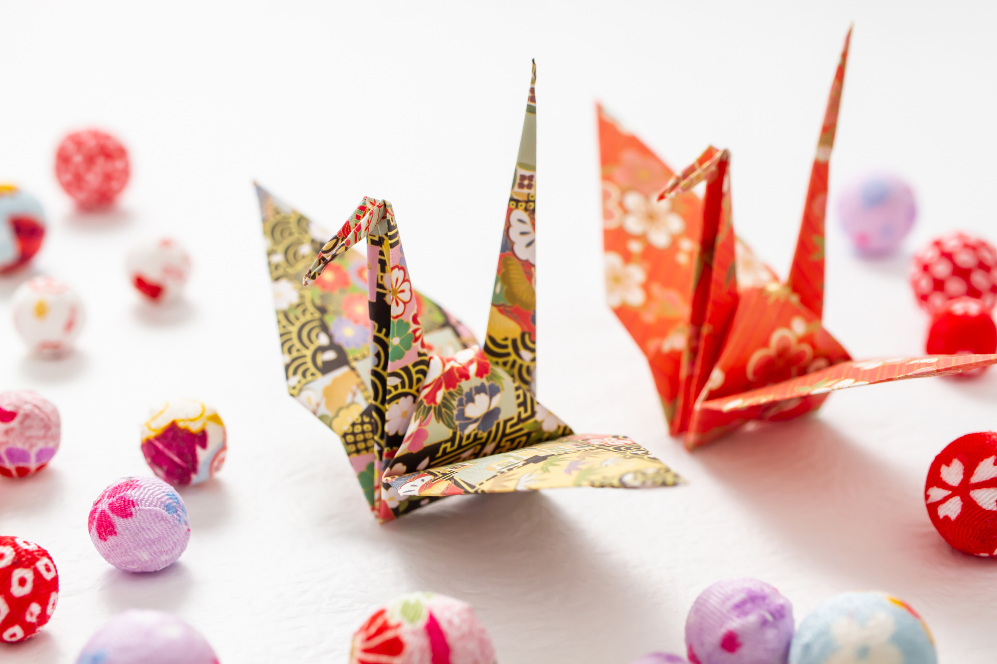 A pair of colorful origami cranes surrounded by vibrant fabric balls  symbolizing the balance and connection fostered through therapy for relationship issues and couples therapy in Portland, Oregon, serving zip codes 97035, 97229, 97214, and 97210.