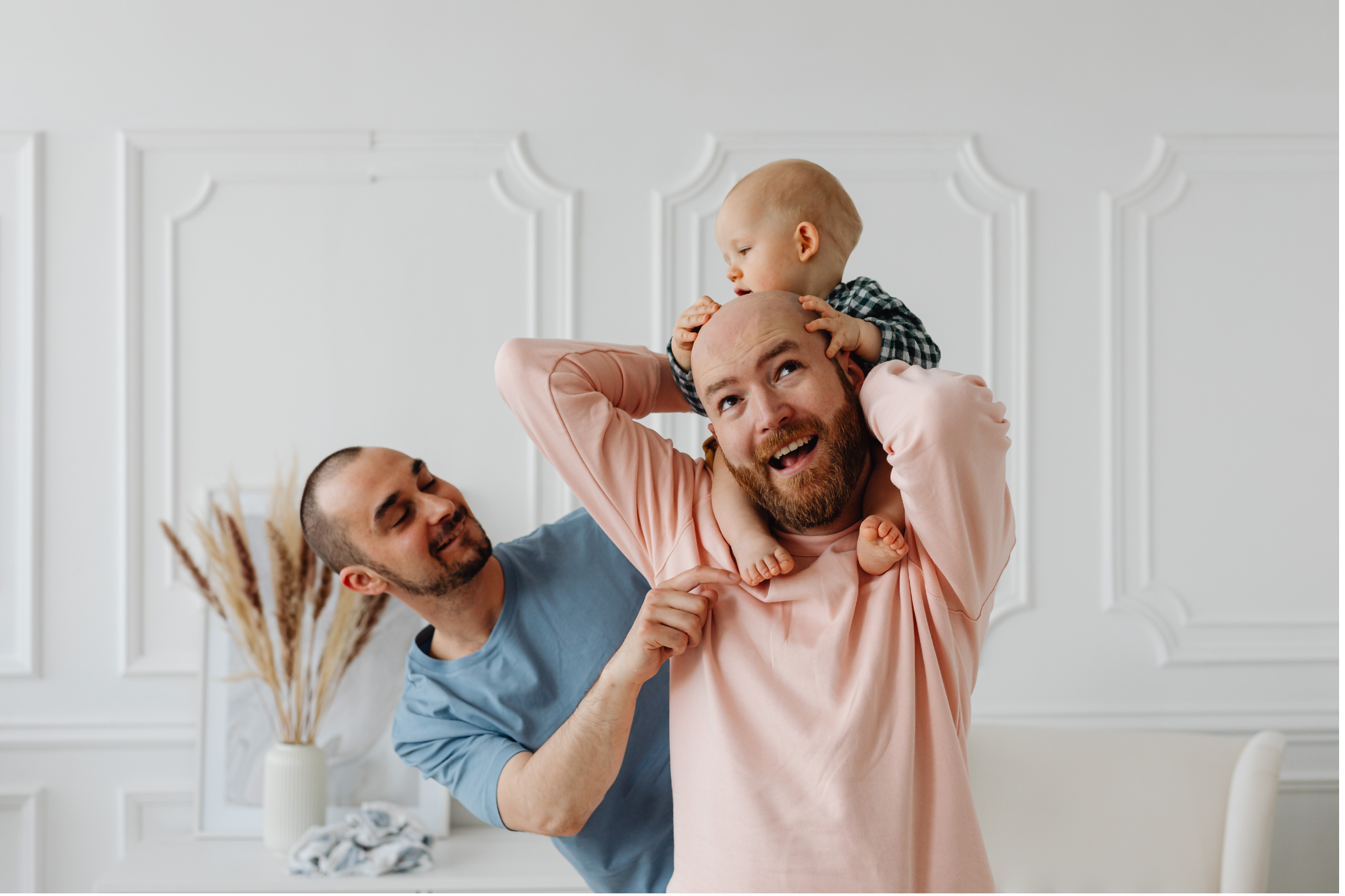 A gay couple holds a baby on their shoulders while another man engages with them in a bright, modern home, symbolizing harmony and connection through learning how to stop fighting and arguing with couples therapy in Seattle and Bellevue, Washington,