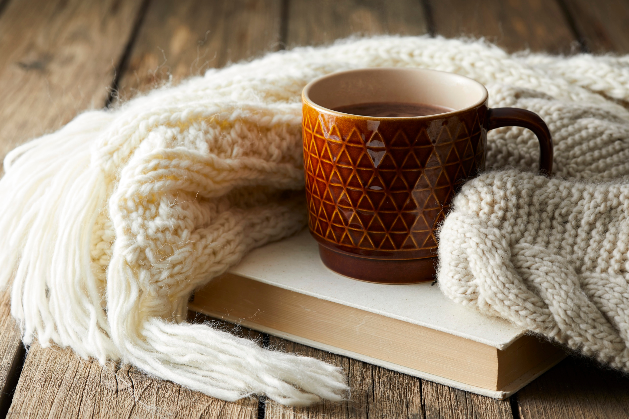 A rustic setup featuring a mug of coffee, a knitted scarf, and a book on a wooden table in Portland, Oregon, or Seattle, Washington, reflecting the introspective and solitary tendencies of avoidant attachment.