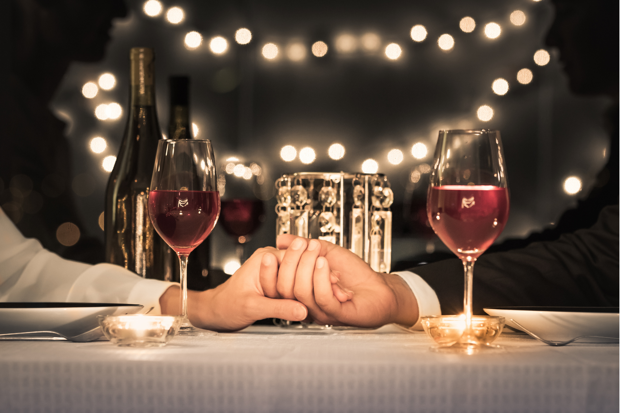 A romantic dinner with clasped hands, representing the connection you desire. Relationship anxiety can make intimacy challenging. We help manage anxiety in relationships, serving clients in Oregon, including zip codes 97214 and 97210.