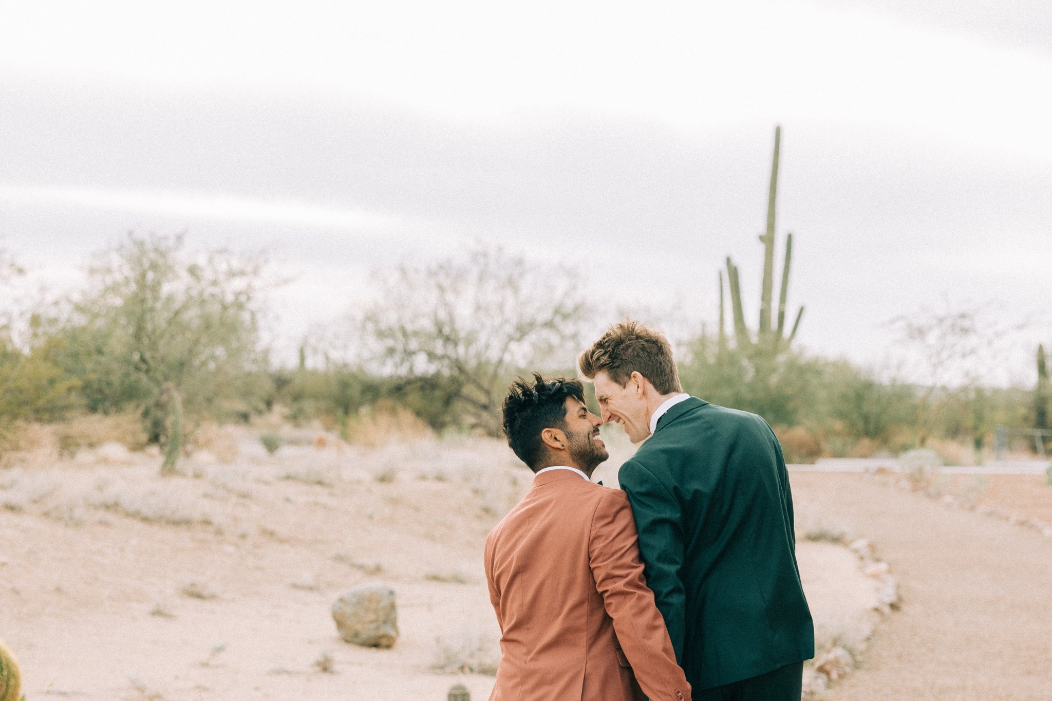 A gay couple sharing an intimate moment with foreheads touching in a serene desert setting. Highlighting attachment styles and trust, this image resonates with couples seeking counseling in Portland, Oregon, near zip codes 97214 and 97210.