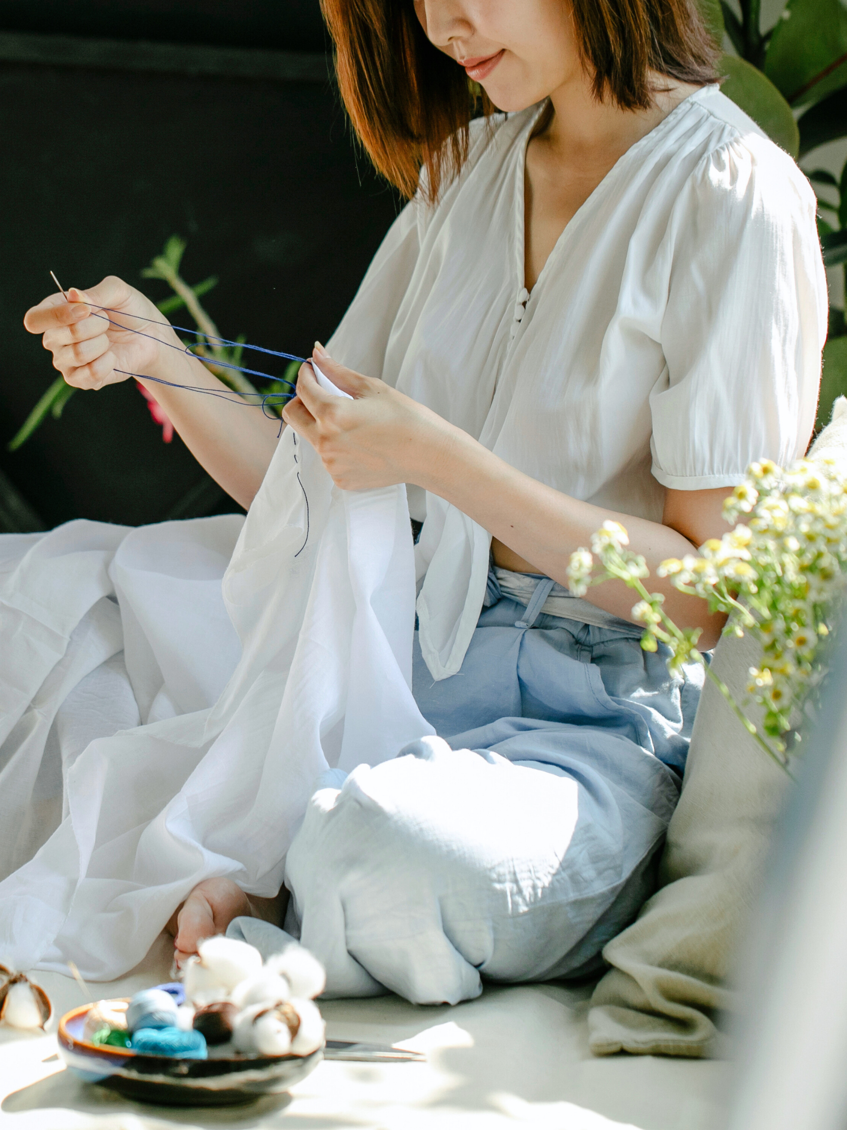 A woman carefully stitches fabric in a sunlit room, symbolizing the detailed work of professional development. Clinical consultation with an AAMFT approved supervisor in Oregon and Washington