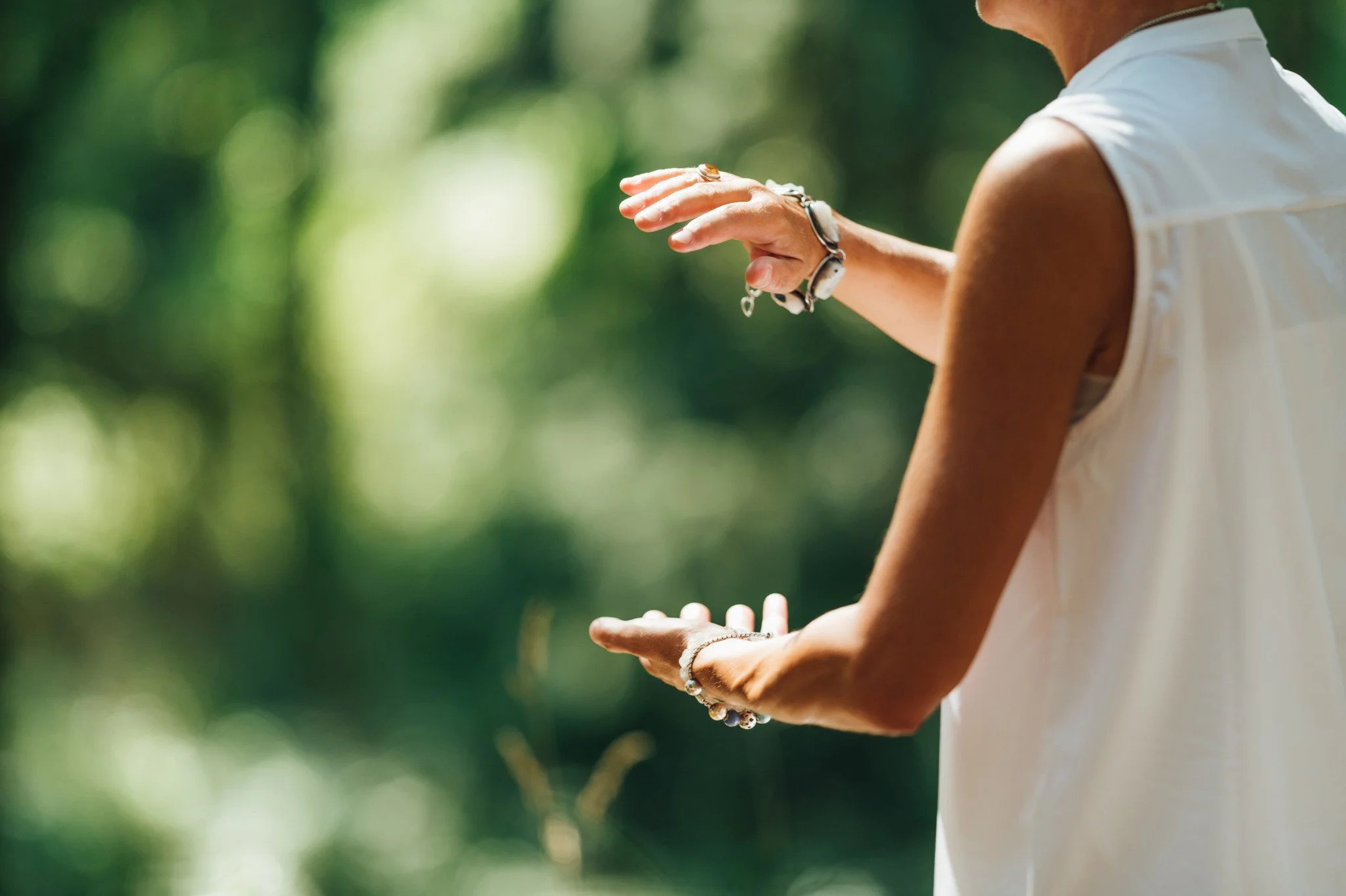 A woman wearing bracelets & doing a breathing technique outside. What are the signs of career burnout? Learn the signs & how burnout therapy in Seattle, WA can help.