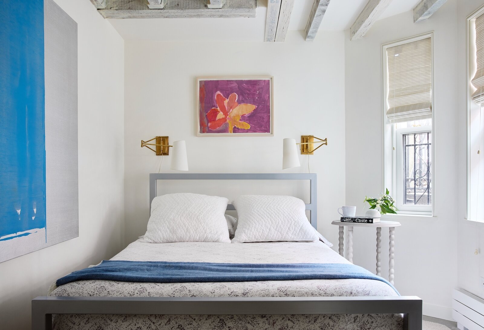  Priscilla’s 23-year-old daughter sleeps here when she visits from the West Coast. The flower painting above the bed is her childhood artwork, and the blue painting is by New York City artist John Zinsser.&nbsp; 