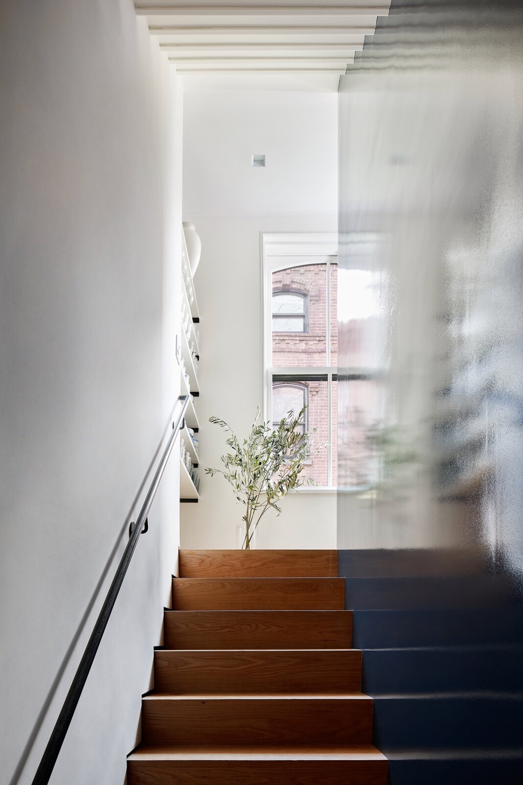  The stairs are hidden behind a core wood block with a high gloss finish for a mirror-like reflection. Fortuitously, there is a window at the top of each run. "They're not perfectly aligned with the stairs, but they bring light down at every level," 