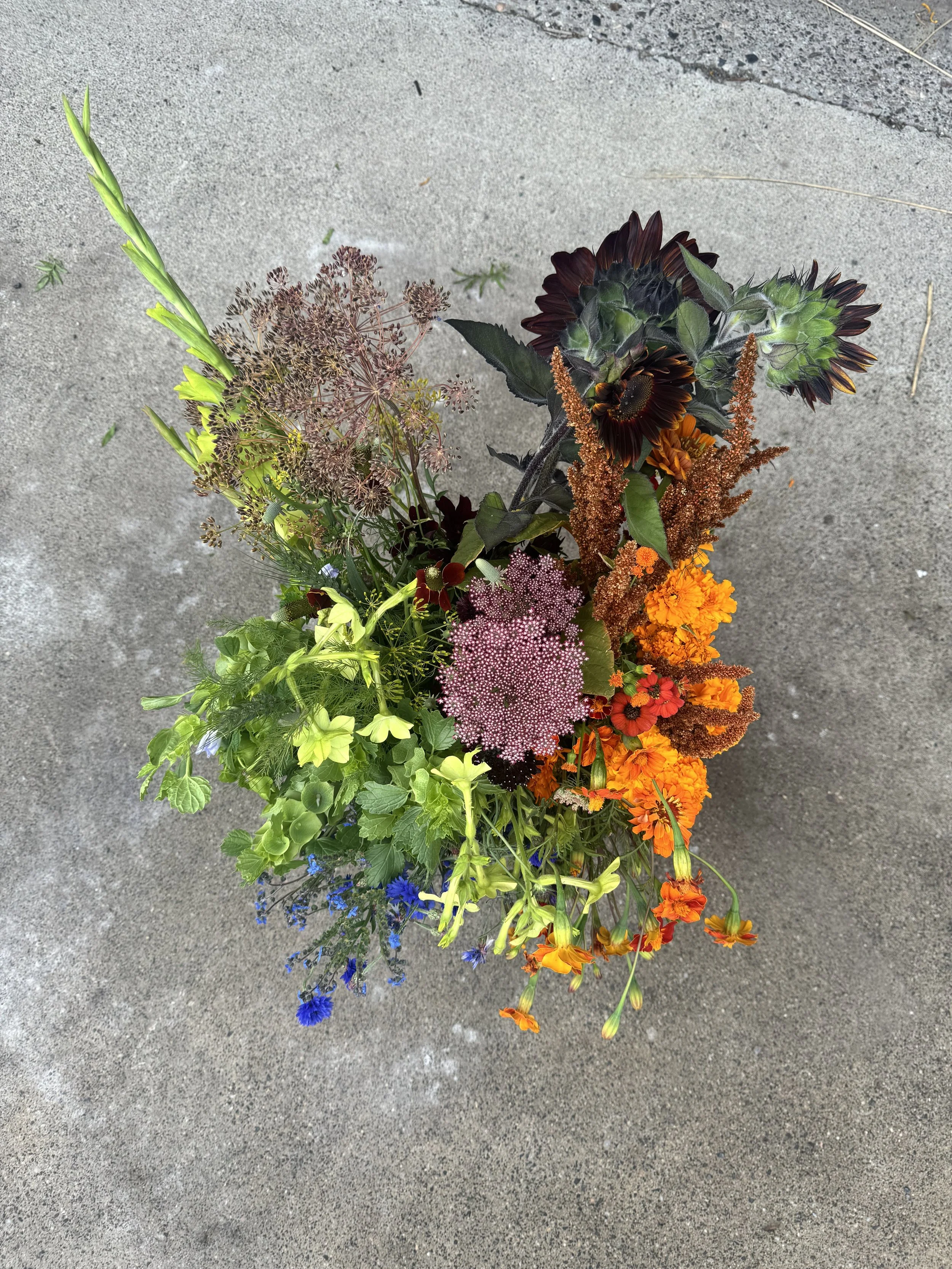 Top-down view of a colorful bouquet of various flowers on a concrete surface.