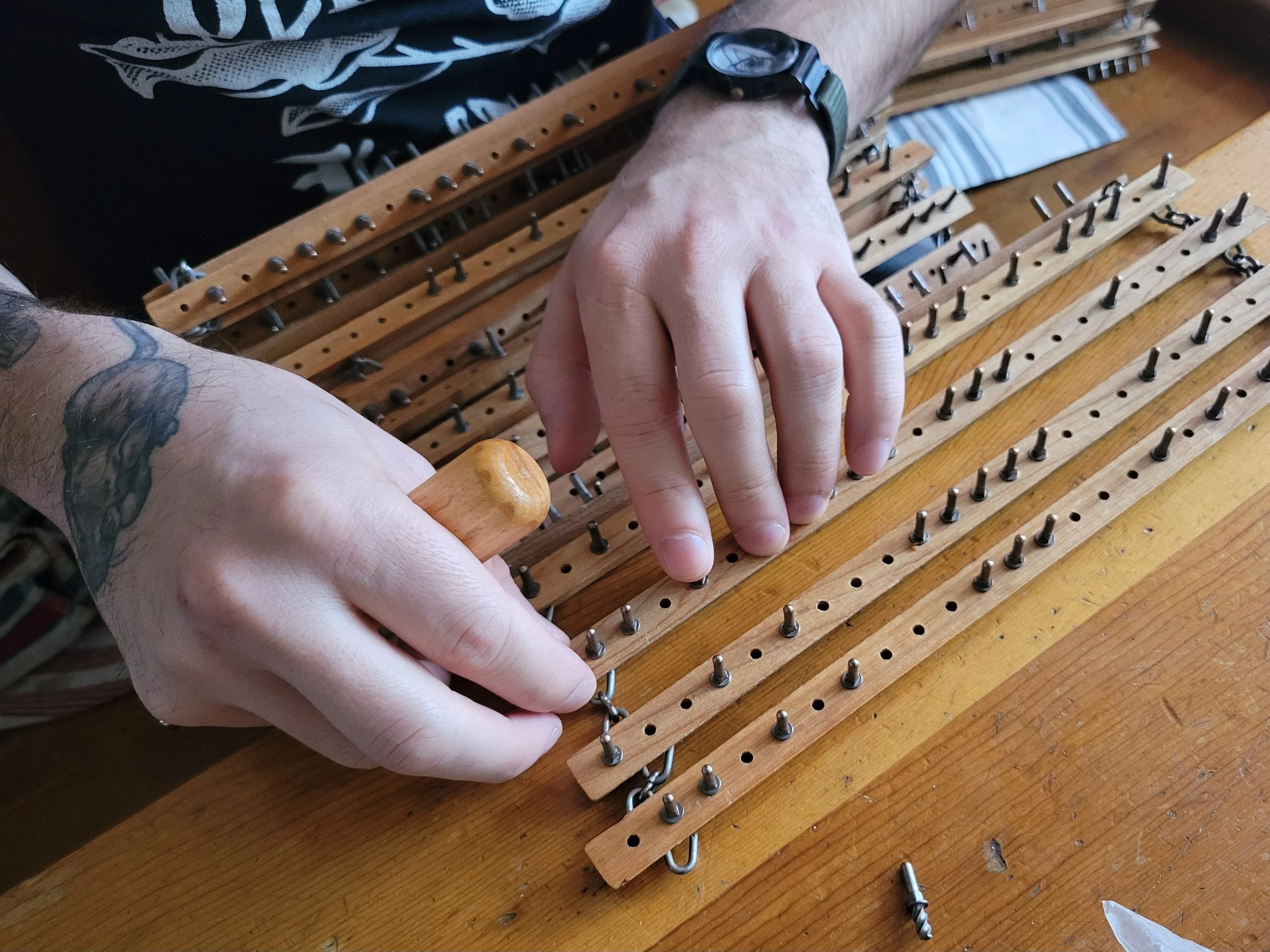 Programming the metal and wooden "dobby" computer that controls the lifting and lowering of warp threads.