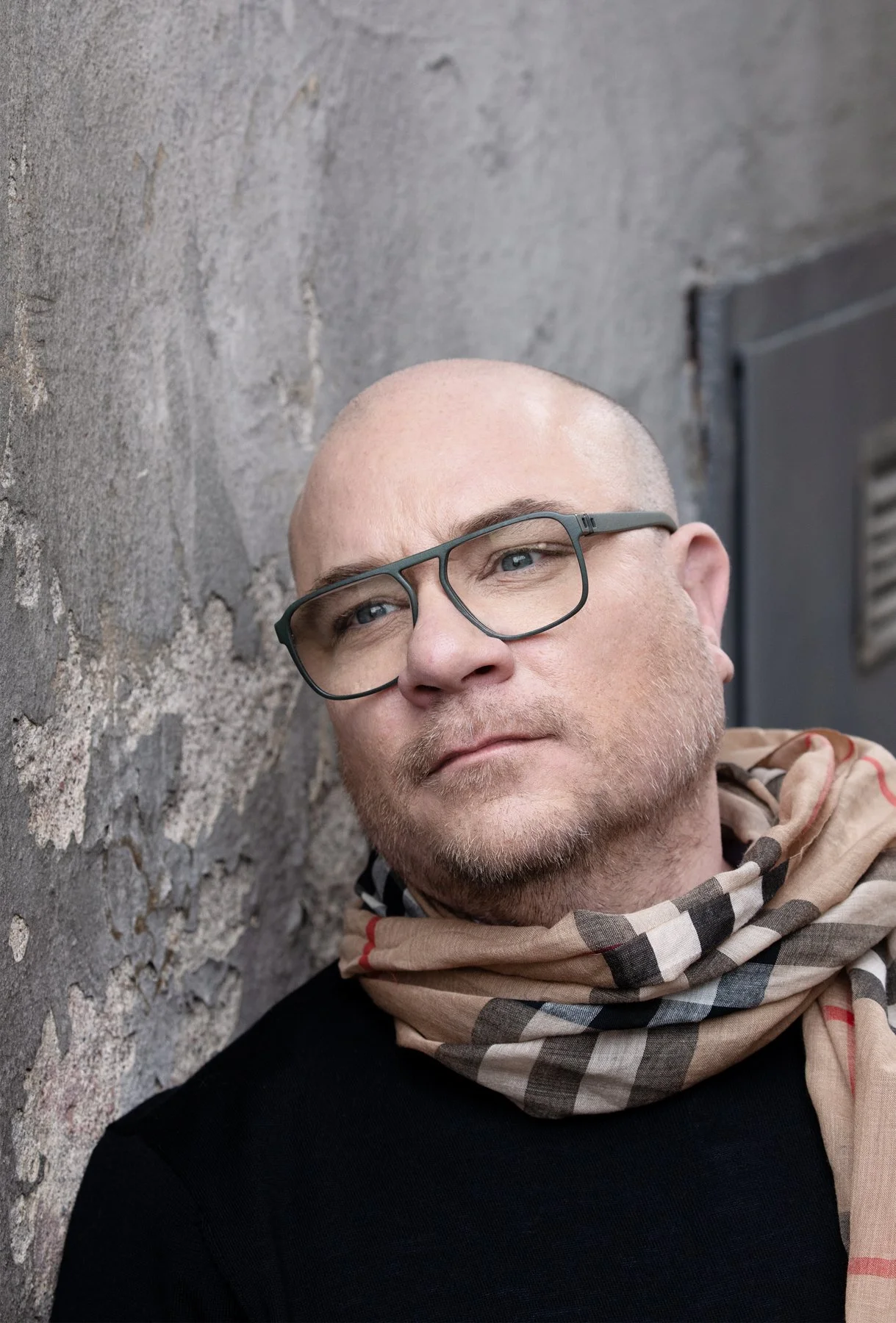 Bild på Anders Bolin med blicken riktad åt sidan genom sina glasögon, med en grå cementvägg i bakgrunden