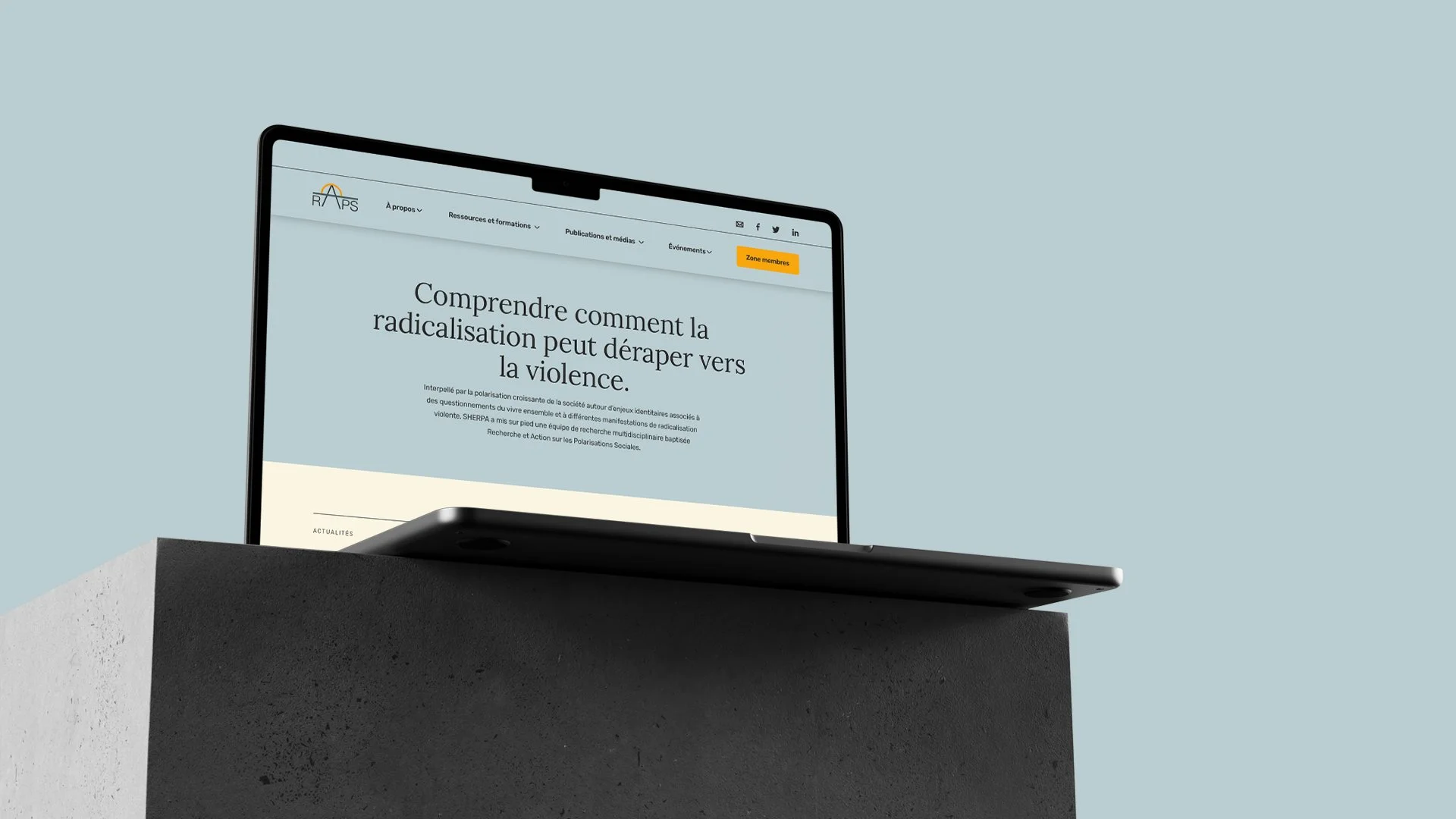 Un ordinateur portable affichant une page web sur la lutte contre la radicalisation et la violence, posé sur un socle en béton contre un fond gris clair.