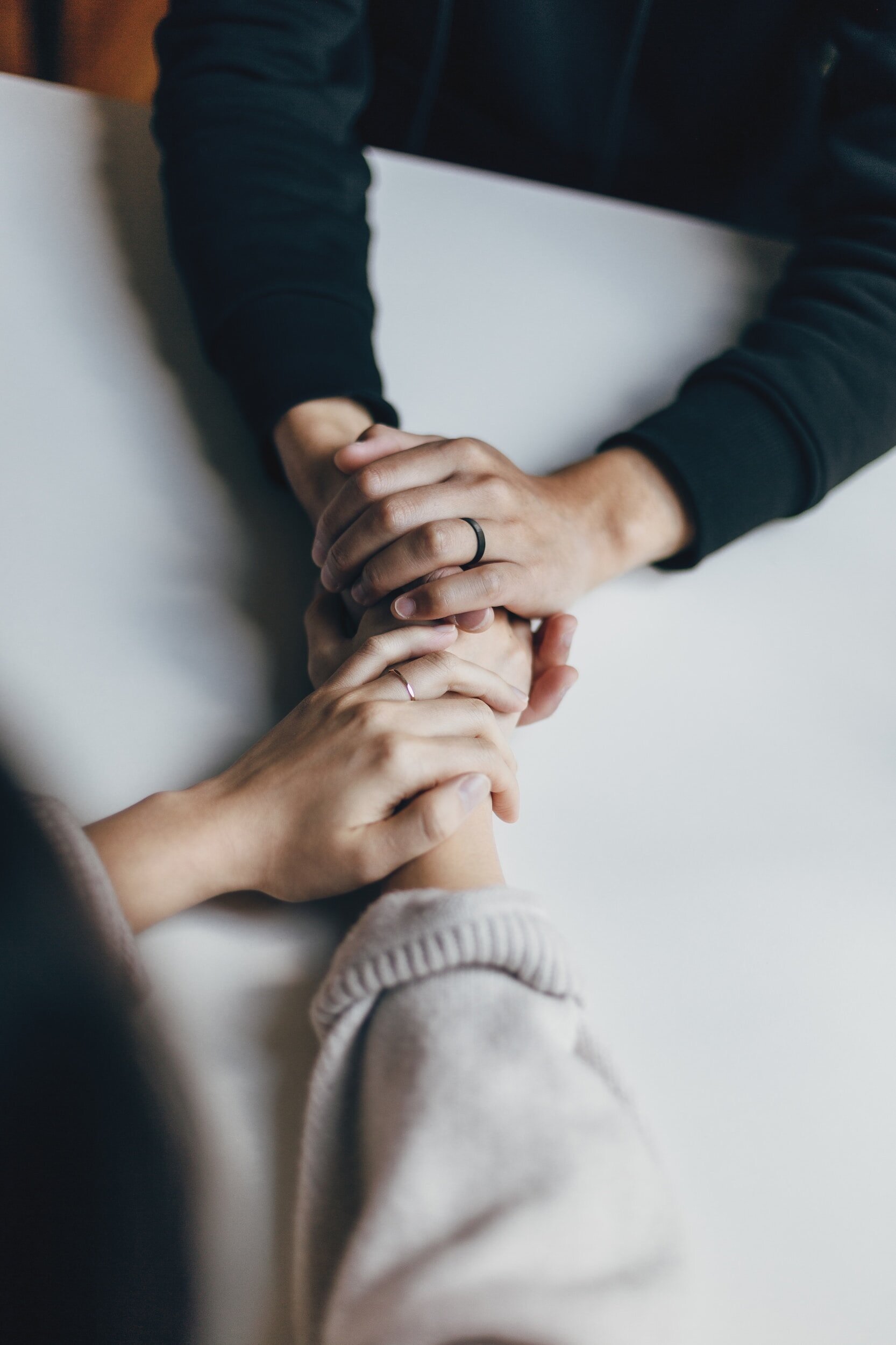 Two people holding hands in a comforting gesture over a table.