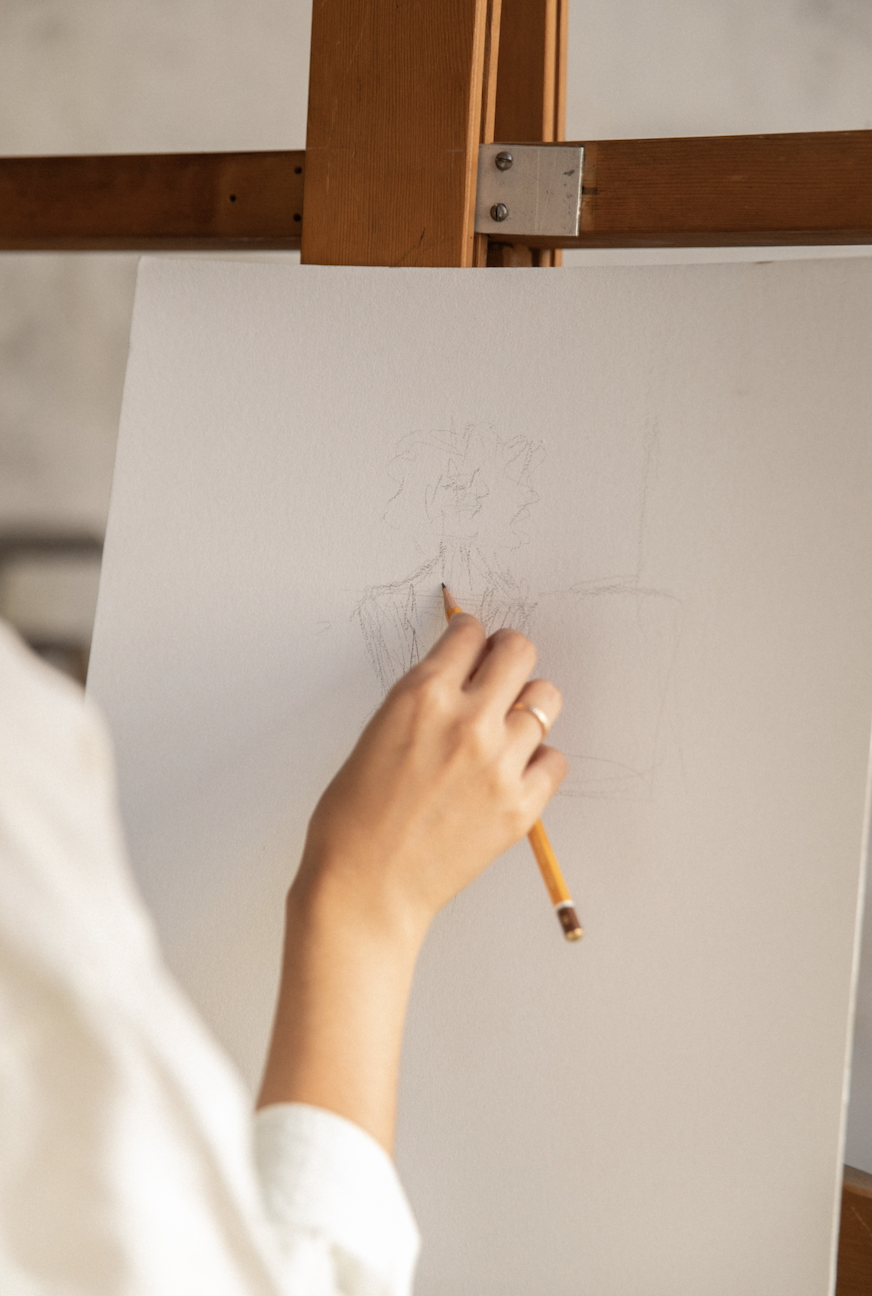 Artist sketching an image of a person at an easel