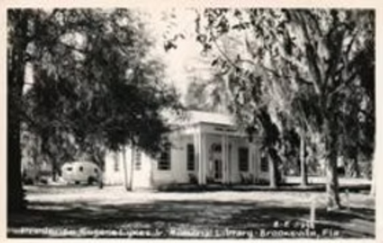 A blurry scan of an early postcard showcasing the bookmobile parked in the back of the library. Looking to replace this image with a more high quality scan