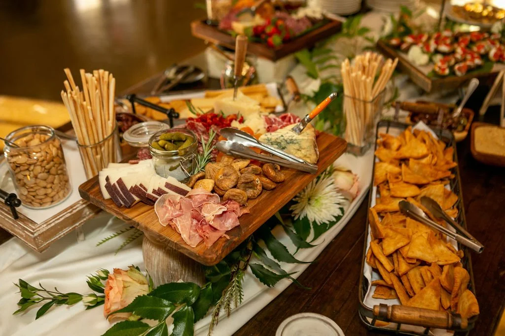 Charcuterie board with meats, cheeses, figs, gherkins, crackers, and breadsticks.