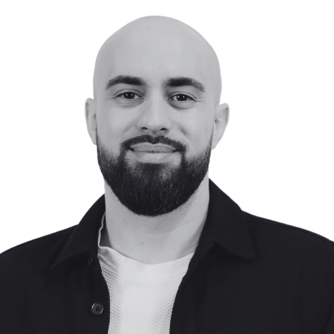 Black and white photo of a smiling man with a beard, short hair, wearing a hoodie.