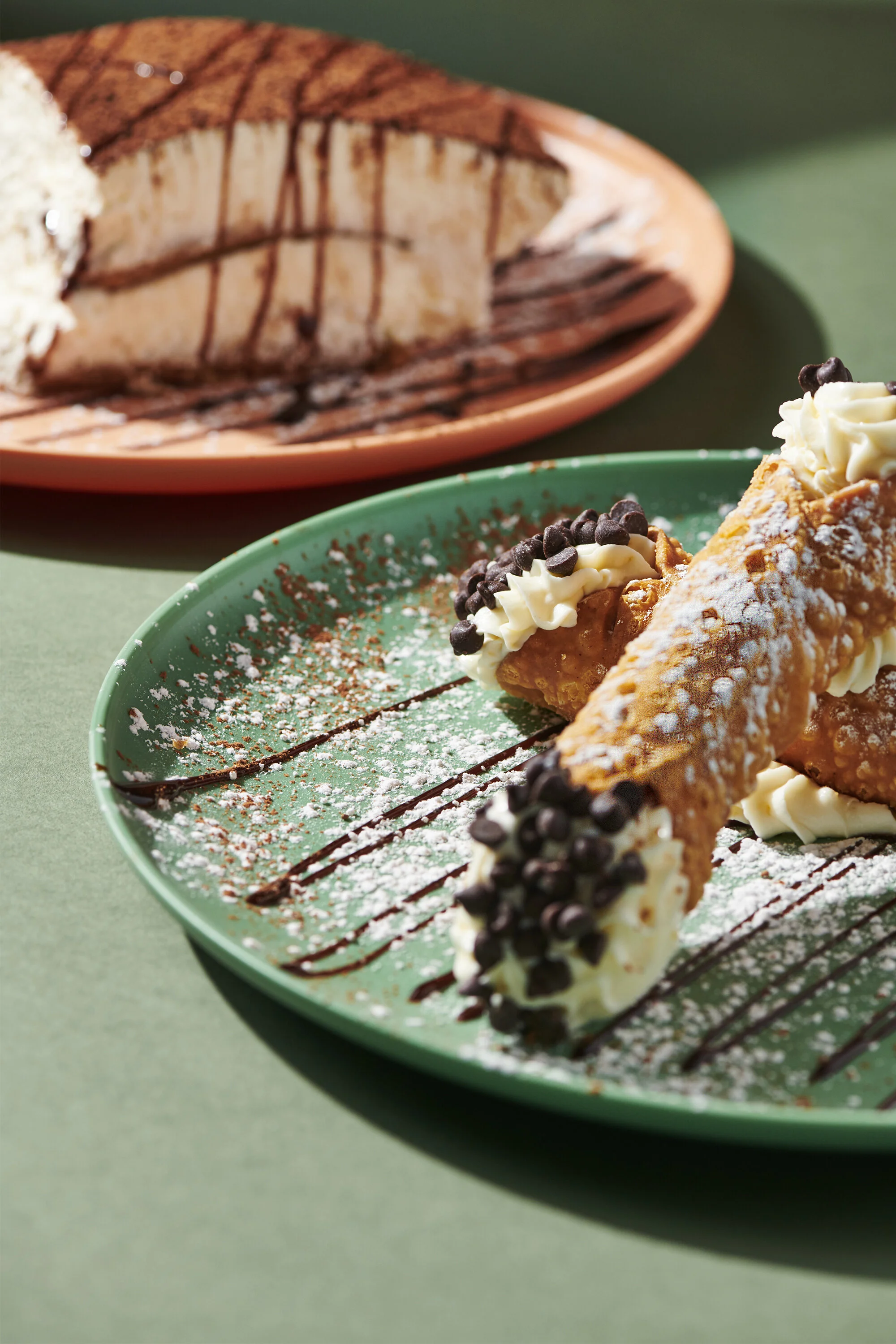 Housemade chocolate chip cannolis at D'Amore's Pizza in Thousand Oaks, with Tiramisu in the background-signature Italian desserts.