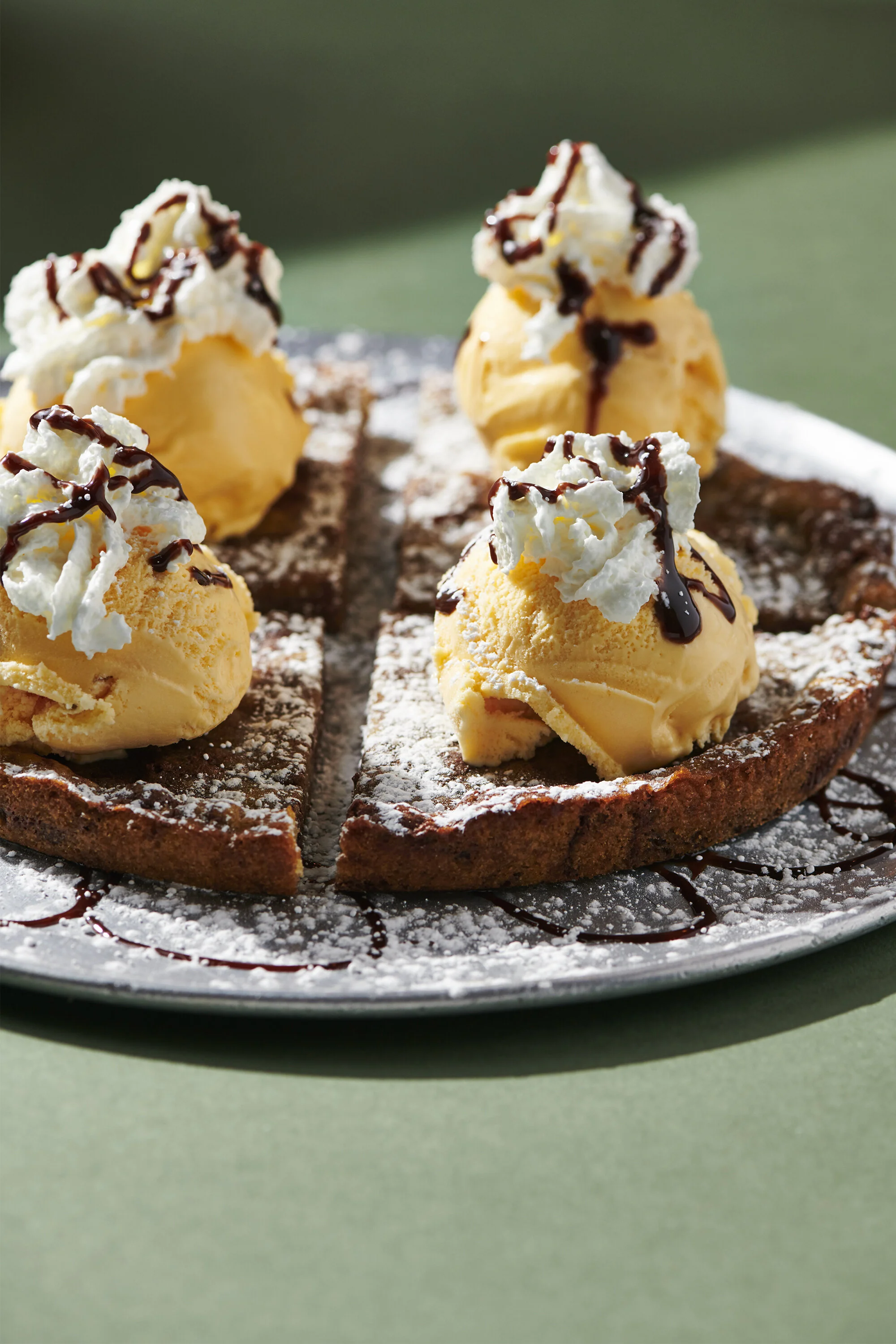 Housemade pizza cookie dessert at D'Amore's Pizza in Thousand Oaks-topped with vanilla ice cream, whipped cream, chocolate syrup, and powdered sugar.