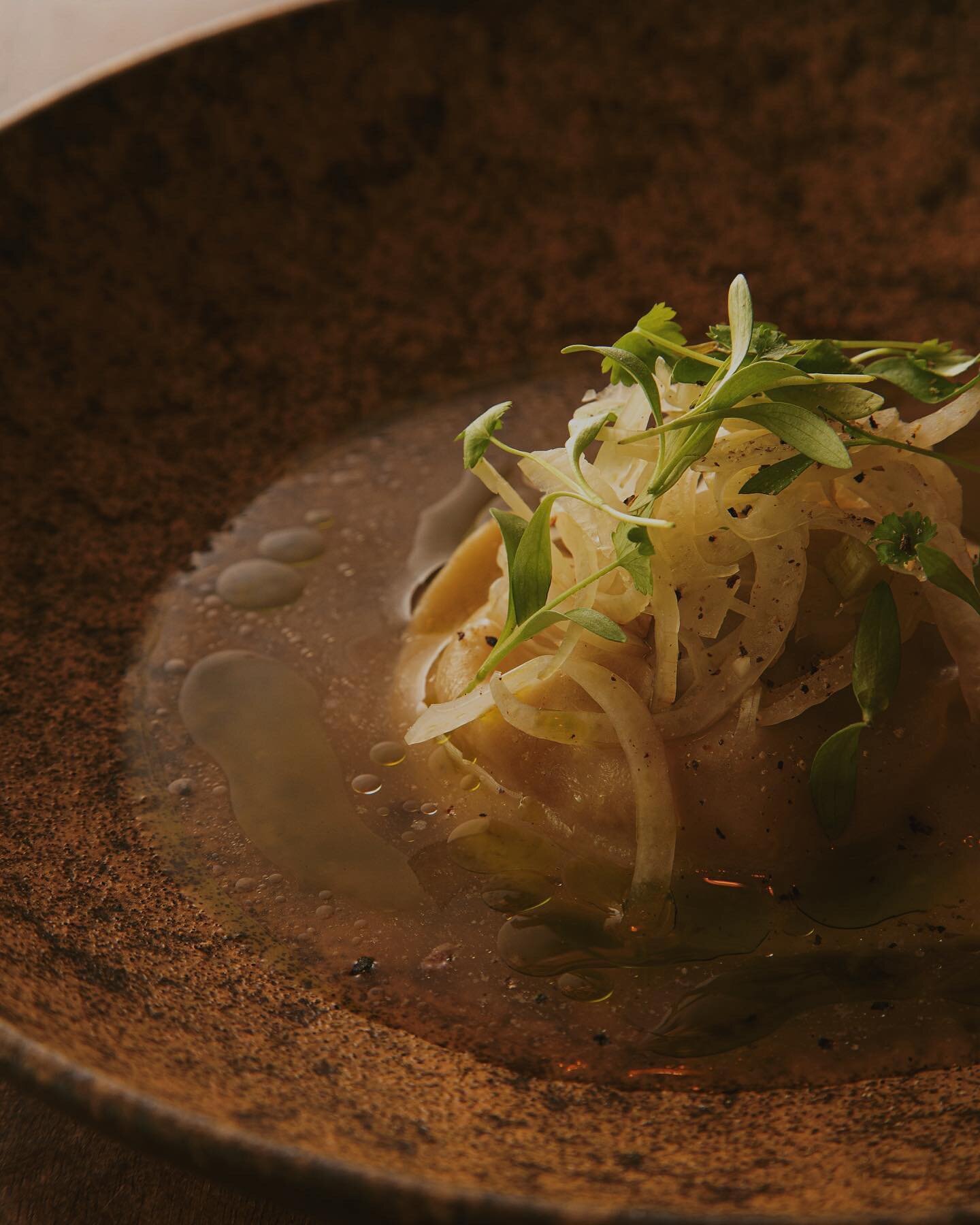 .
Big Island Lamb Raviolo. 
The pasta is adorned with sliced fennel and micro cilantro then immersed in a chicken-beef bone broth which is infused with cilantro oil. We season the dish with preserved black peppercorns from Puna Gardens on the Big Isl