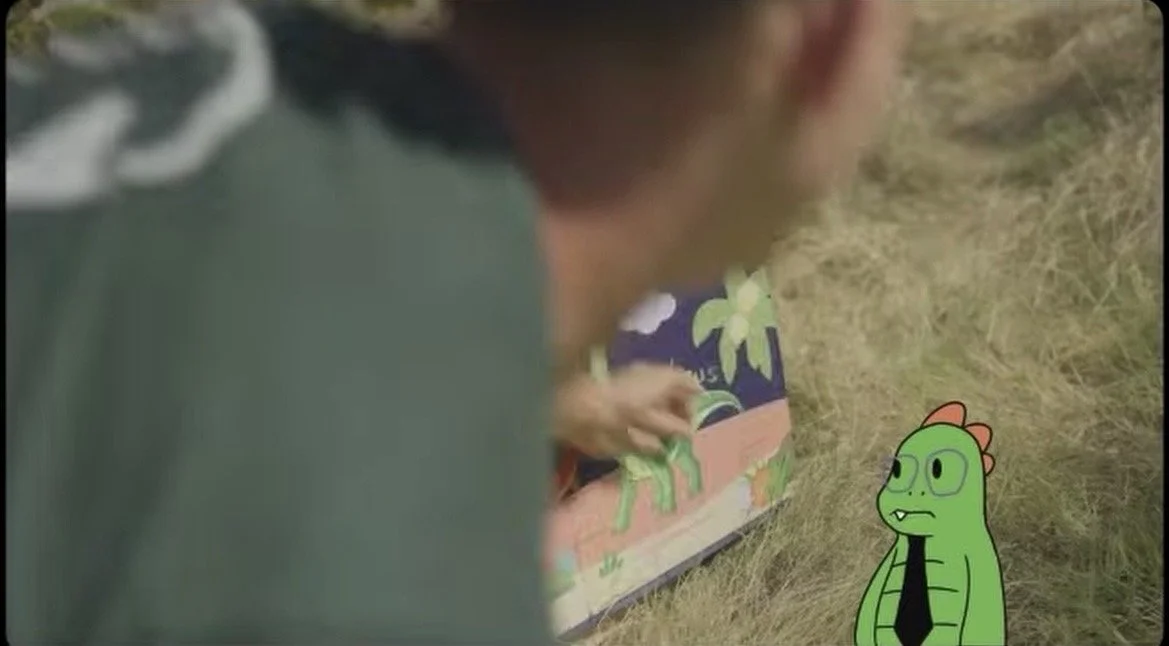 A man (Joseph Hunt) stares at an animated dinosaur
