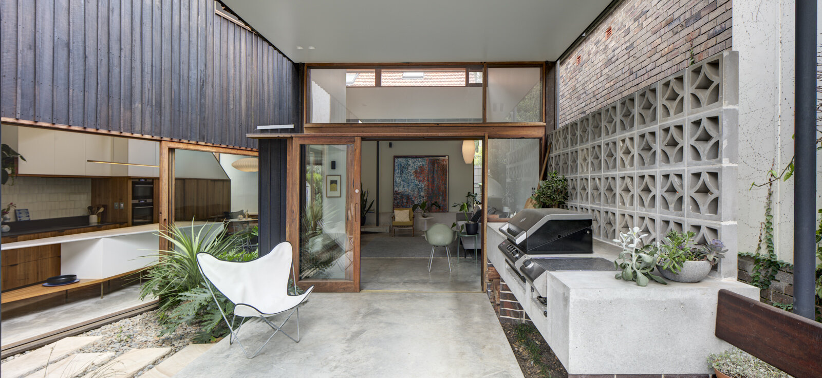 Exterior view of Double stacked sliding glazed doors on concrete sills with fixed glazed highlight windows above.