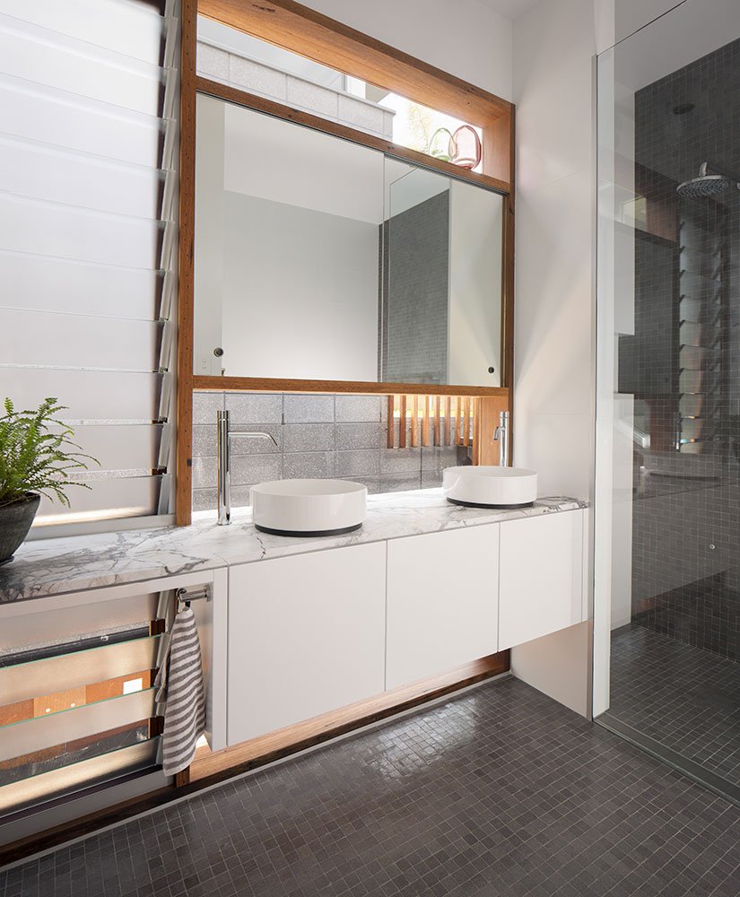Interior view of bathroom featuring fixed opaque glass louvered windows and integrated window/mirror unit all made from recycled Australian hardwood.