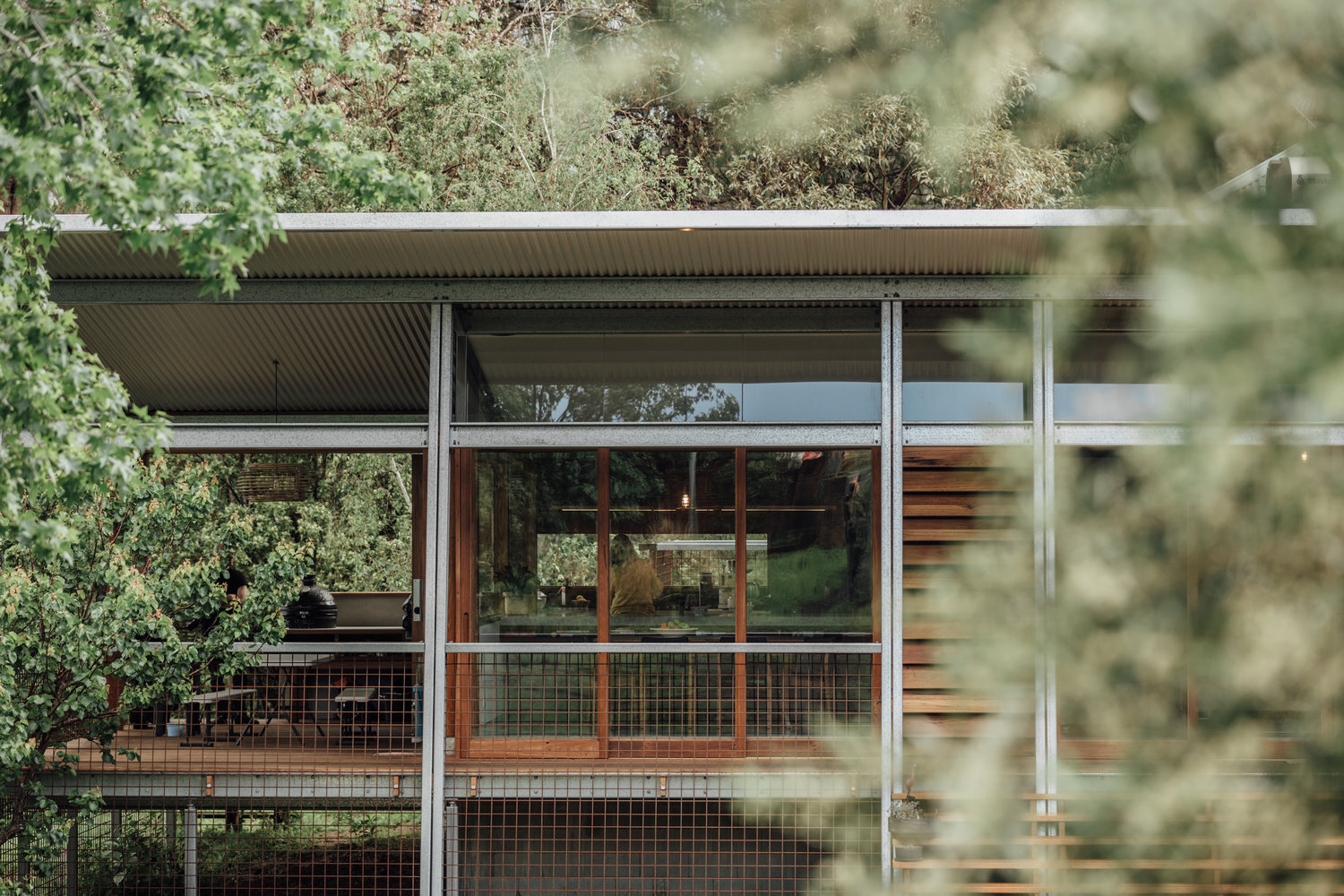 External view of fixed glazed window-walls and sliding glazing door made from recycled Australian hardwood adjacent to large timber deck.