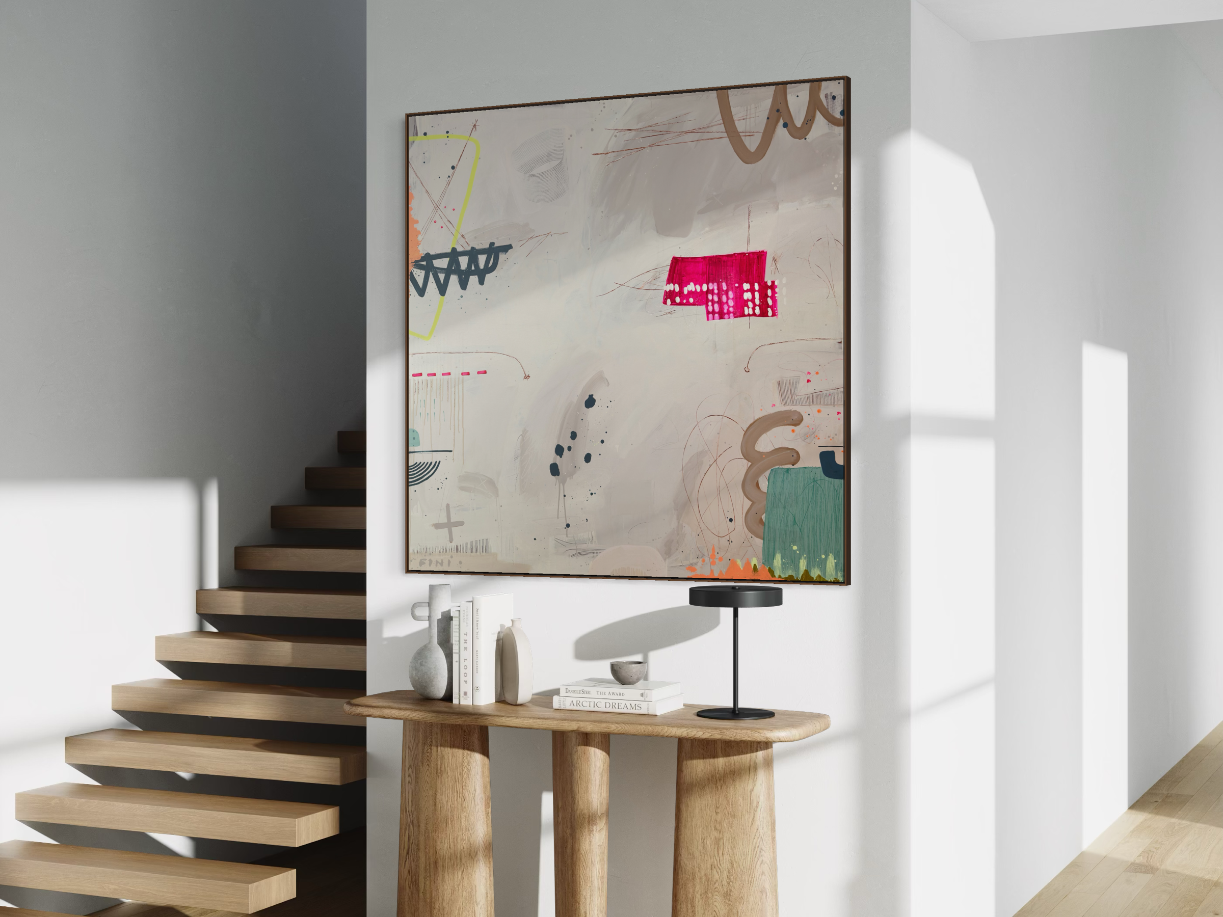 Living room corner with stairs on the left, a large abstract artwork on the wall, and a wooden table with decorative items and books.