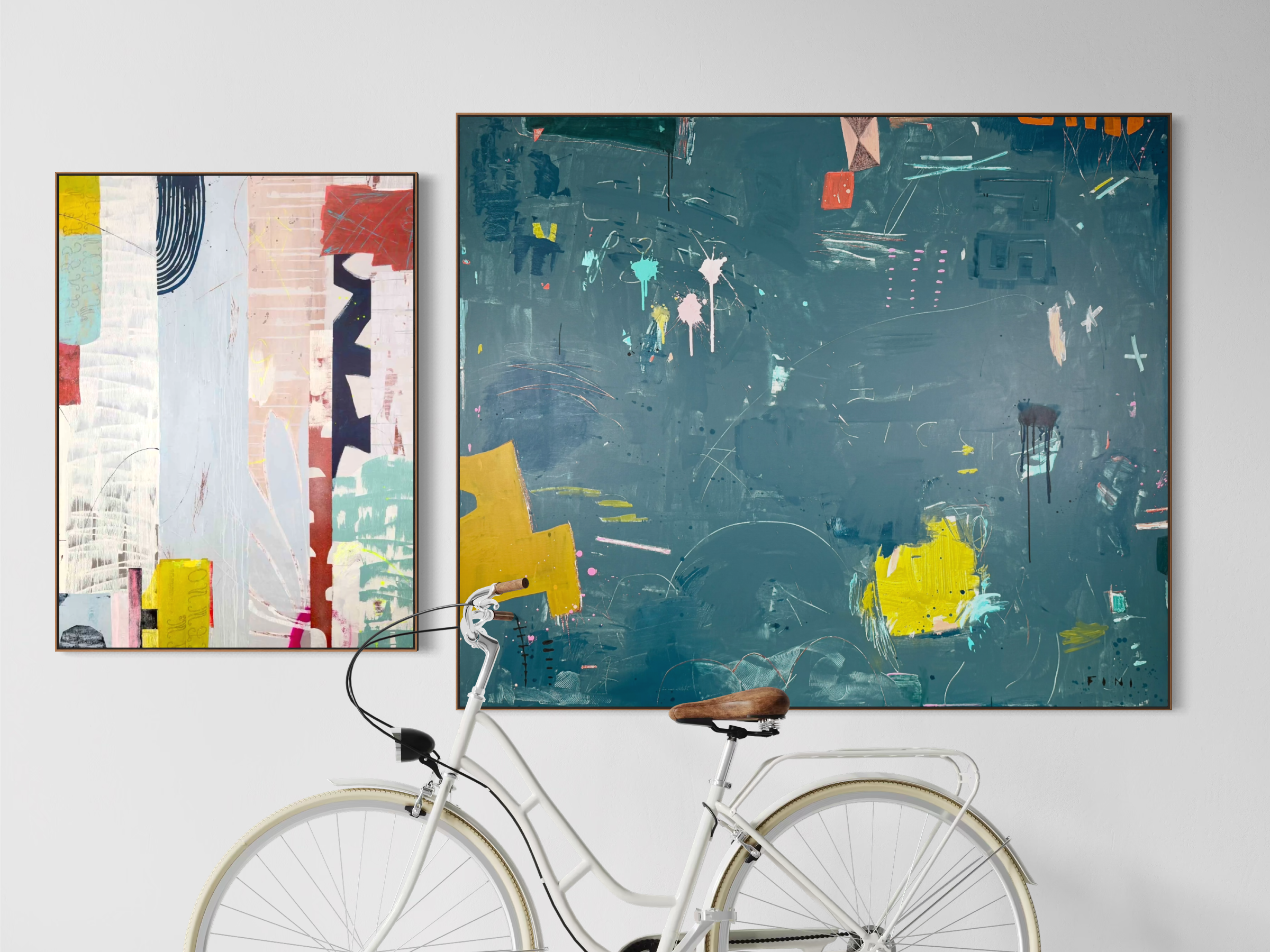 Interior scene with two large colorful abstract paintings on a white wall, and a white bicycle with brown seat and handlebars parked in front of them.
