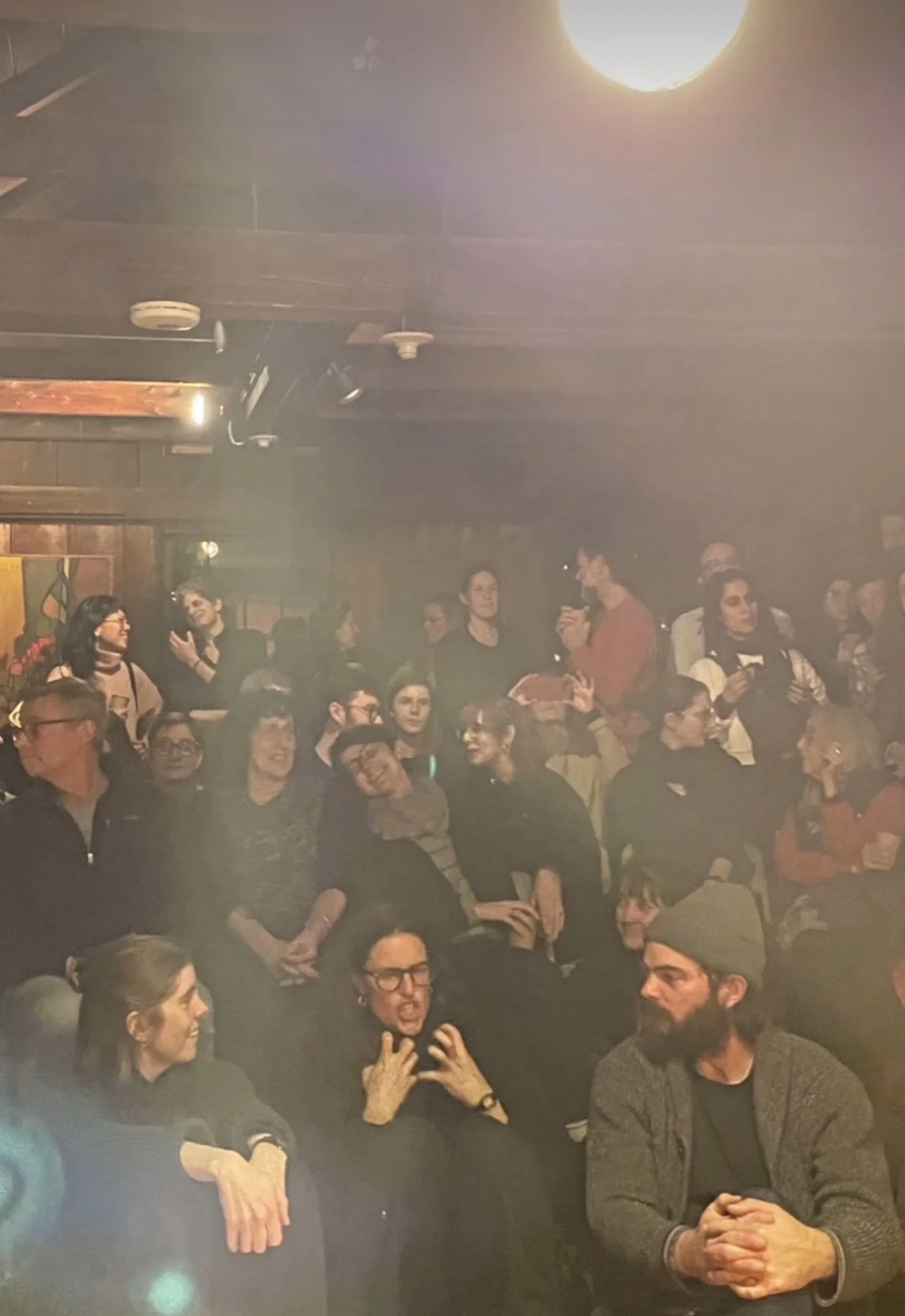 A full audience seated close together in the Barn at the Old Schwamb Mill, Arlington, MA, during the Winter Solstice gathering, December 2025.