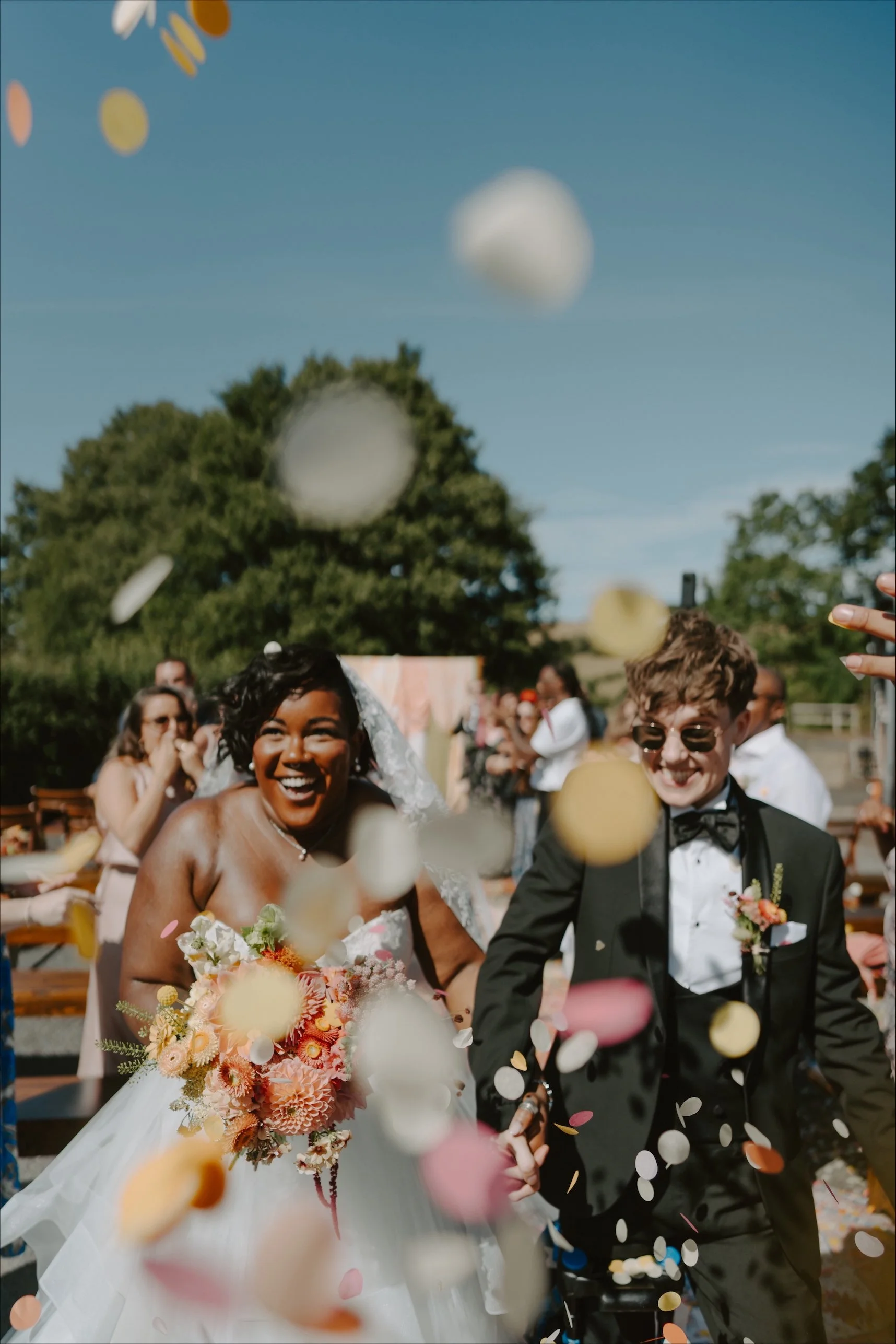 LGBTQI+ couple walking through confetti arch on wedding day