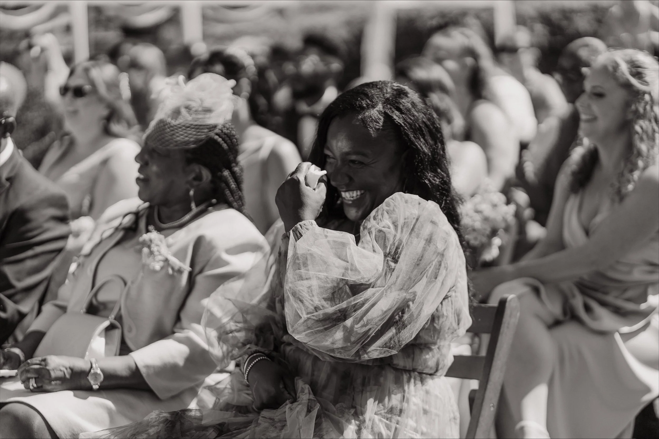 happy guests laughing and crying at wedding ceremony in black and white photo