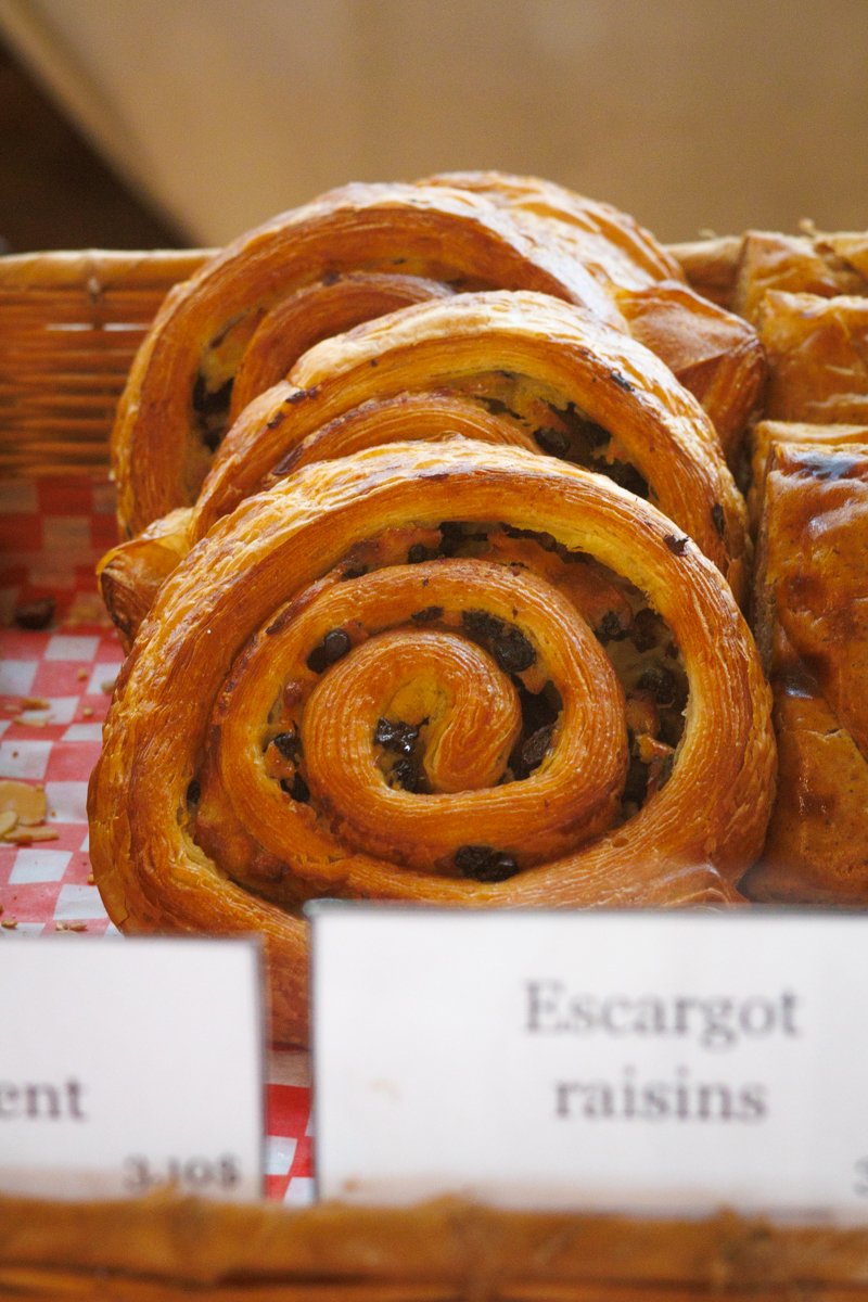 Un pain feuilleté en spirale avec des raisins secs, placé dans un panier en osier.