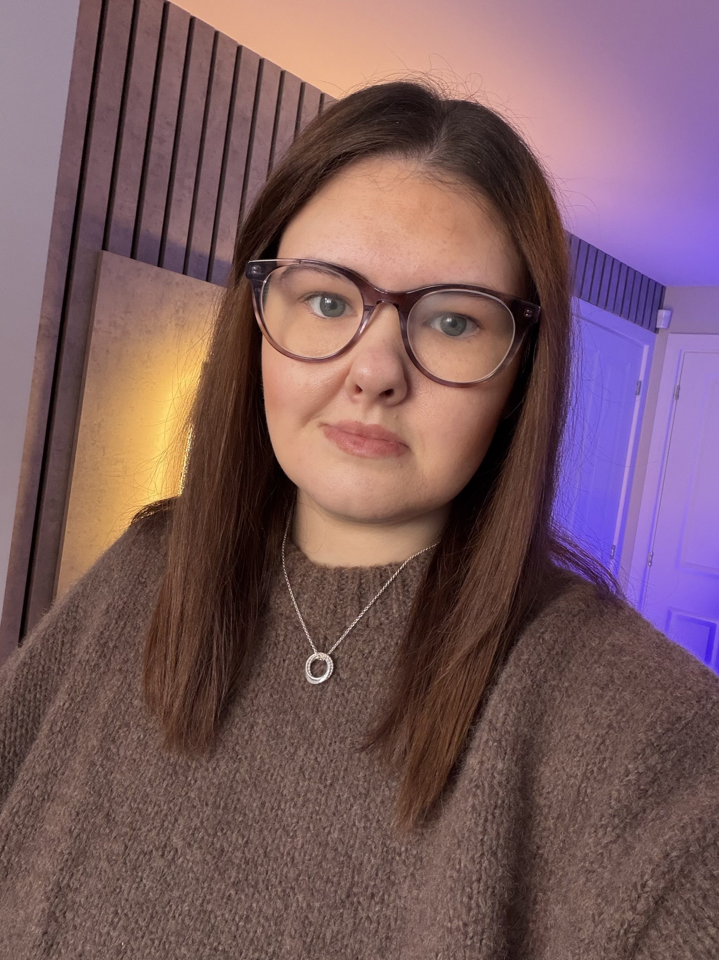 Person with long hair and a black shirt standing indoors.