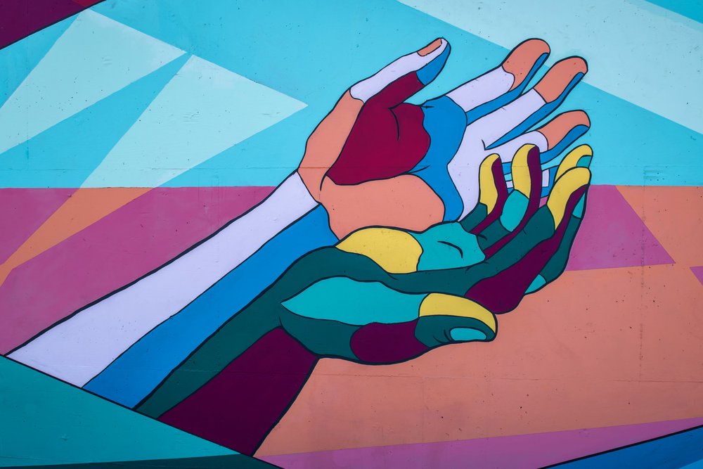 Painted hands of different colors working together in divorce mediation