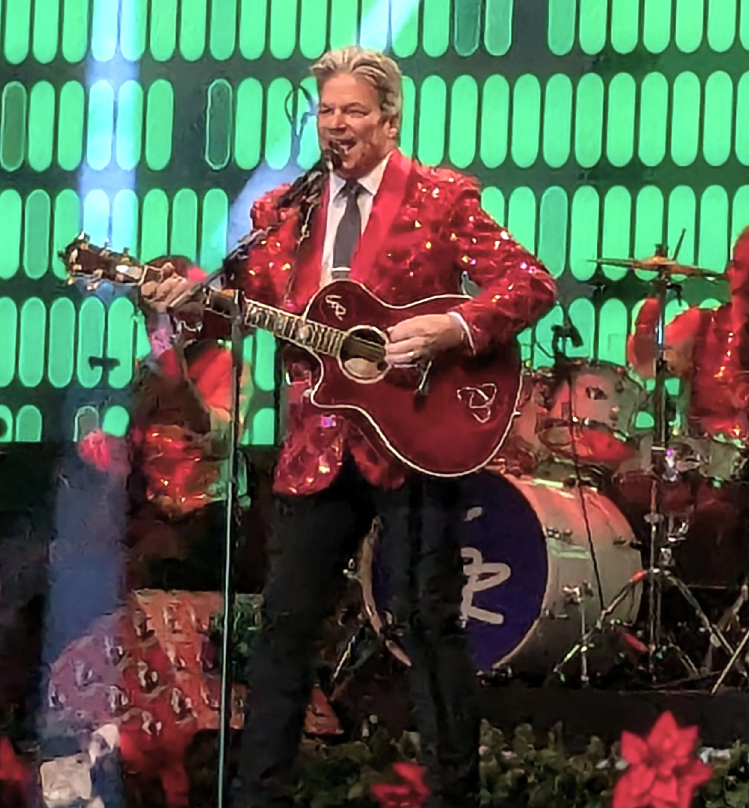 Greg Rowles holding a guitar and performing on stage