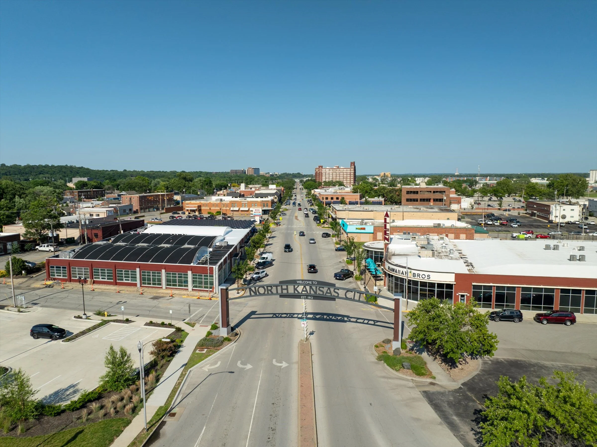 Bird's eye view of North Kansas City with a street running through the center, surrounded by commercial buildings and parking lots, under a clear blue sky.