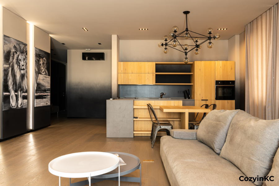 Modern furnished Kansas City apartment with open kitchen, dining area, sofa, and warm wood cabinetry