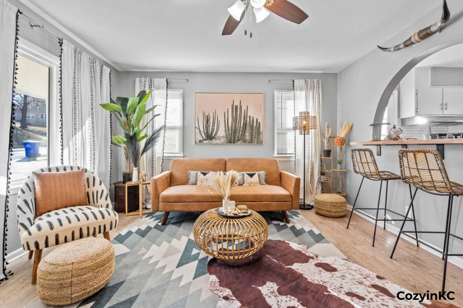 Cozy Kansas City vacation rental living room with leather sofa, patterned rug, rattan decor, and kitchen bar seating