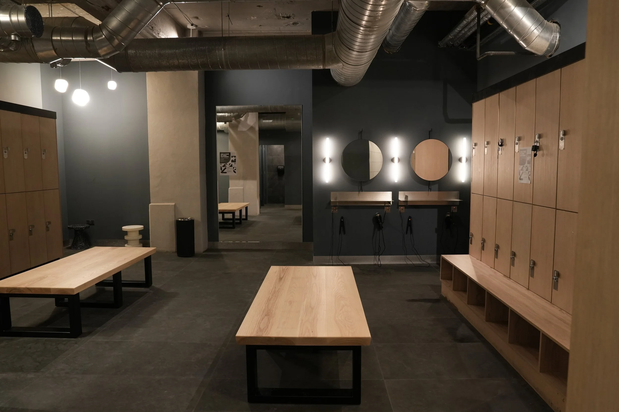 Modern gym changing room with lockers, industrial-style ceiling, shower access. Premium fitness facility locker room with clean design, private showers, and secure storage. Ideal for luxury gym, or health club branding.