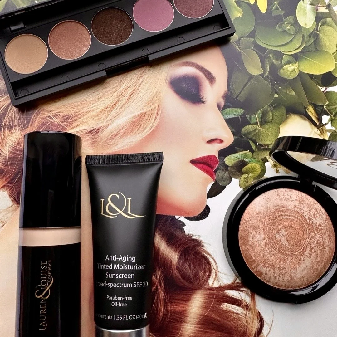 Flat lay of makeup products including an eyeshadow palette, tinted moisturizer, foundation, and a compact powder, with a model's face in the background.