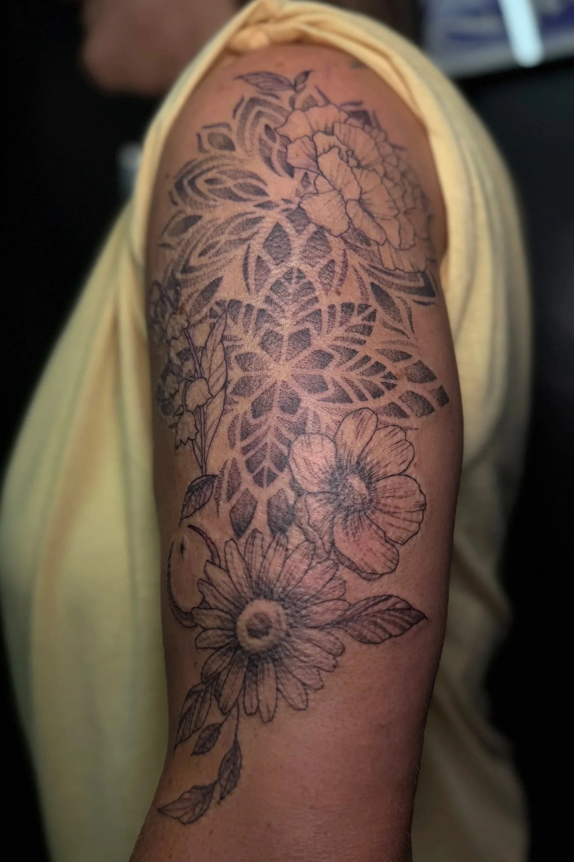 A tattoo of flowers and leaves on a person's upper arm.