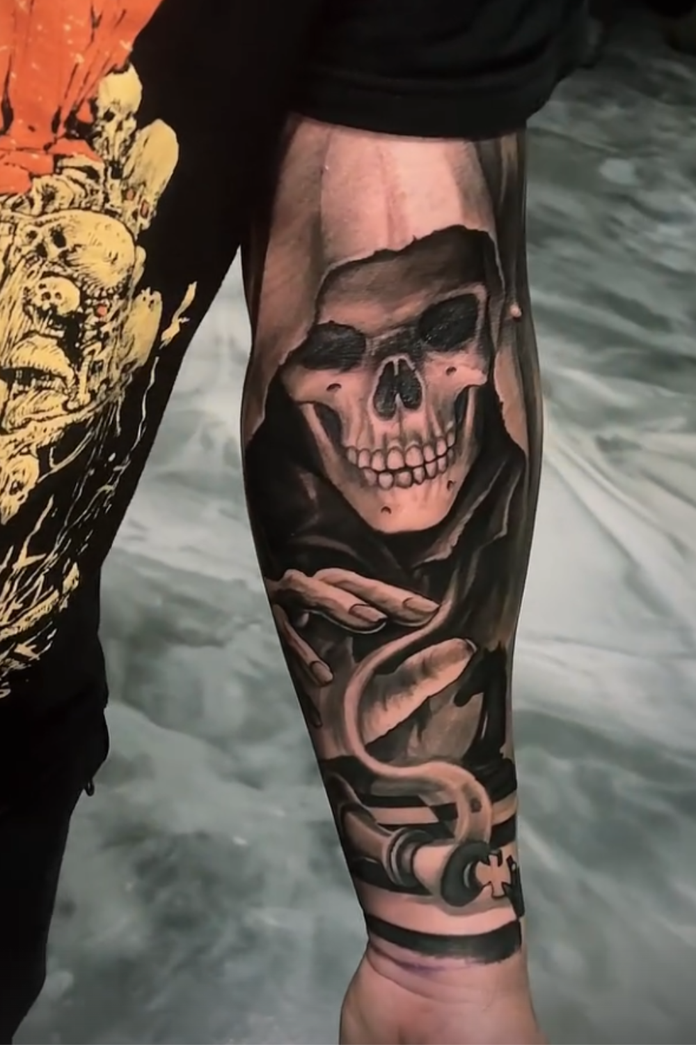 A tattoo of a realistic skull with a dark background on a person's forearm.